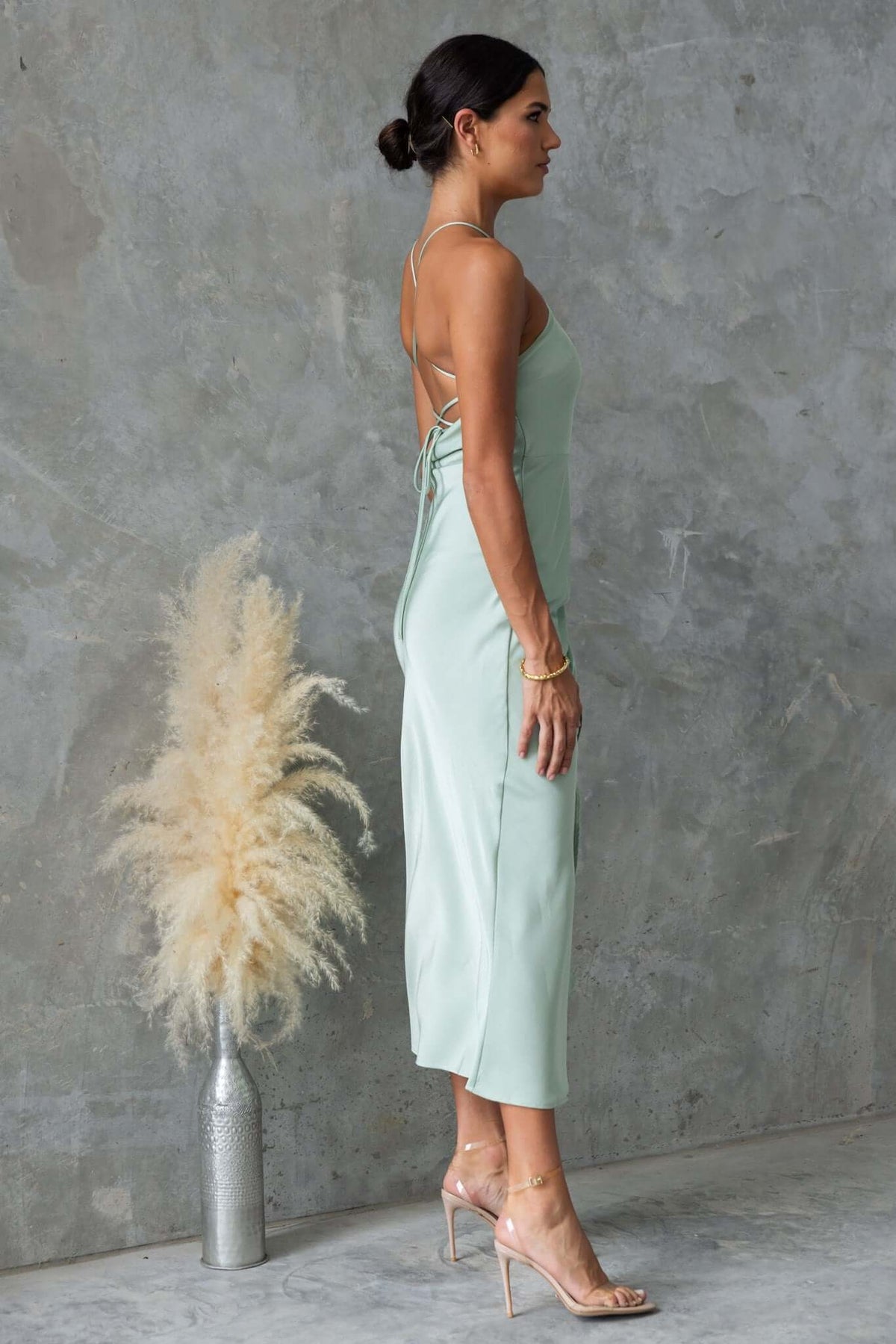 Side view of a woman in a mint green Farida Maxi Dress with adjustable tie straps and asymmetric hem.