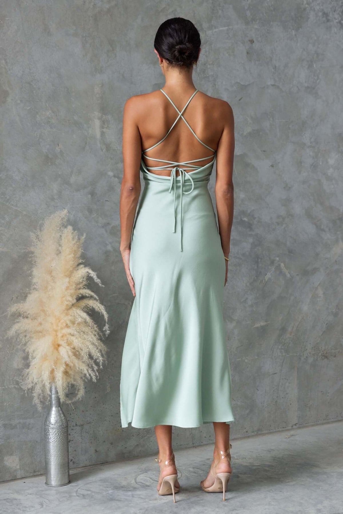 Back view of Farida Maxi Dress in soft green with adjustable tie straps and asymmetric hem.