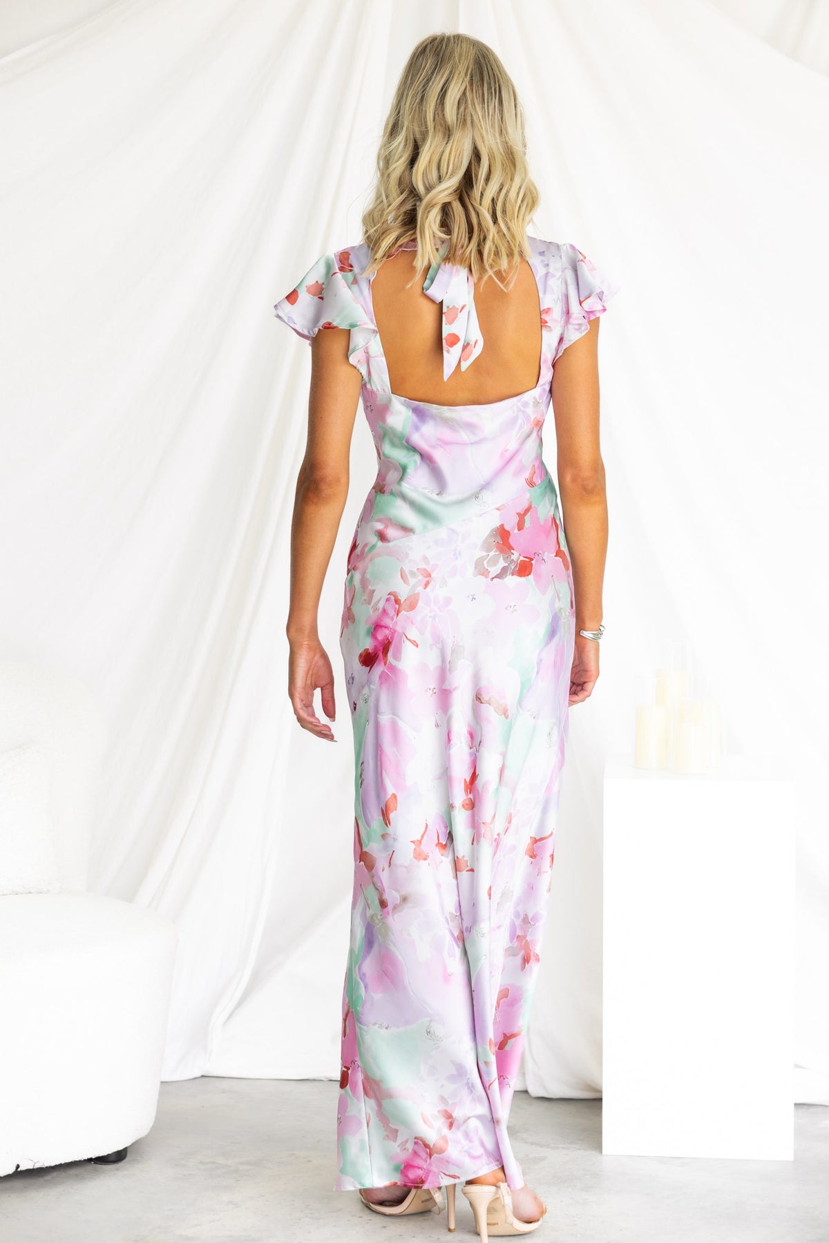 Woman wearing Kindred Maxi Dress in floral print, showcasing the back and tie detail, perfect for summer occasions.