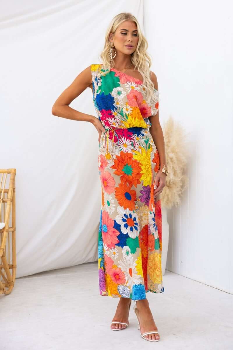 Sicilian Sun Maxi Dress featuring a vibrant floral print, asymmetric neckline, and stylish tie detail.