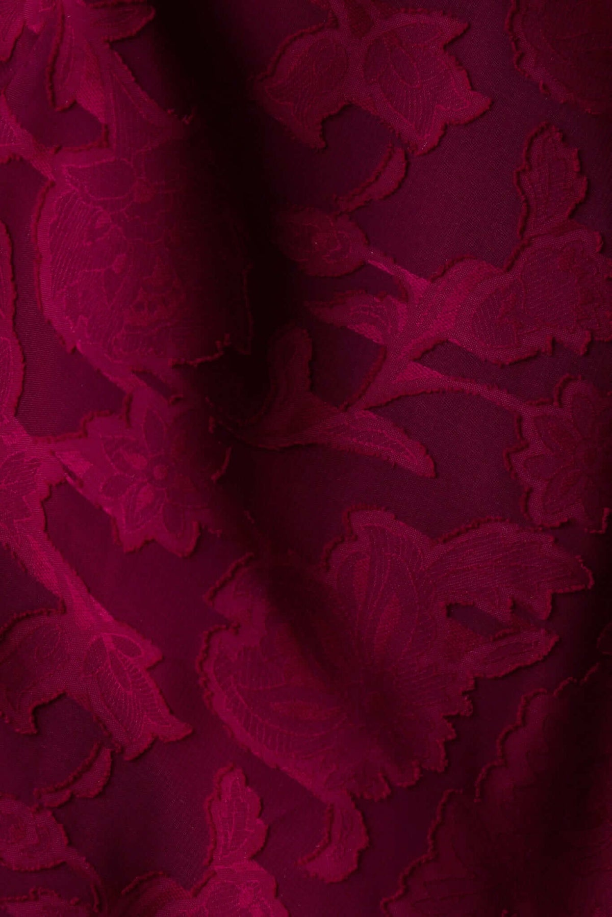 Close-up of textured burgundy fabric with floral patterns, ideal for a stylish maxi dress.