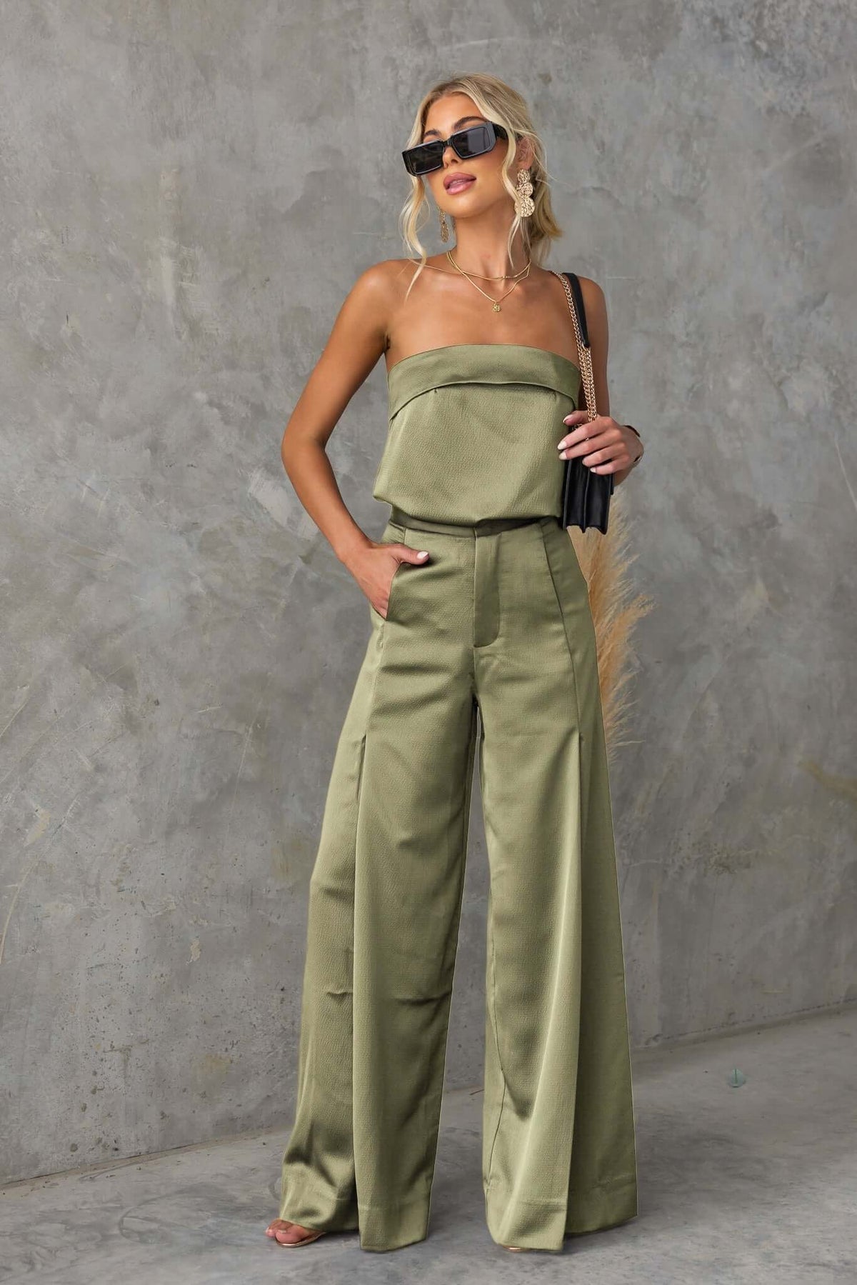 Chic woman wearing olive Hampton style pants with wide legs and pockets, accessorized with sunglasses and a trendy handbag.