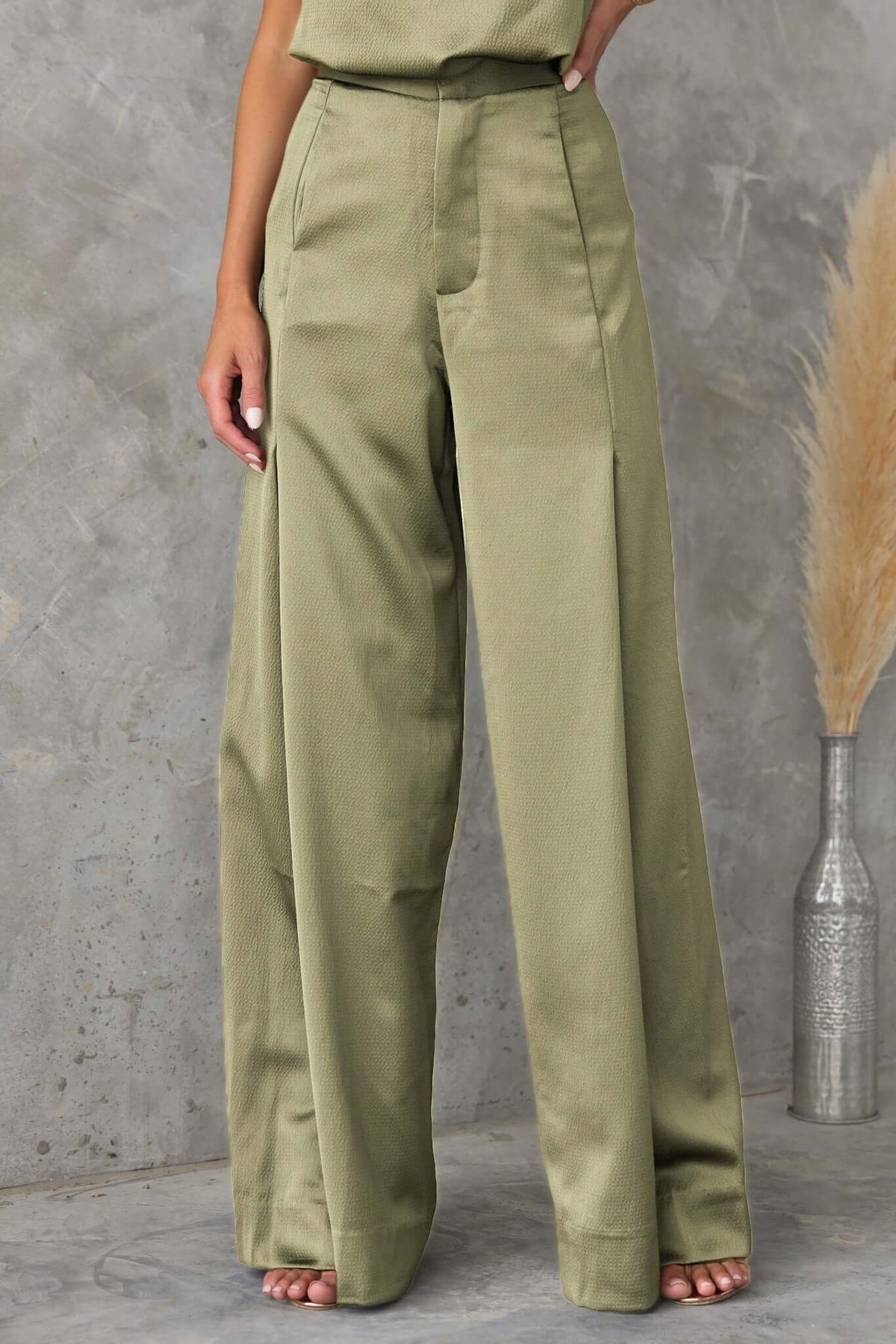 Hampton style pants featuring a mid-high waist fit, wide legs, and pockets in a sleek olive green color.