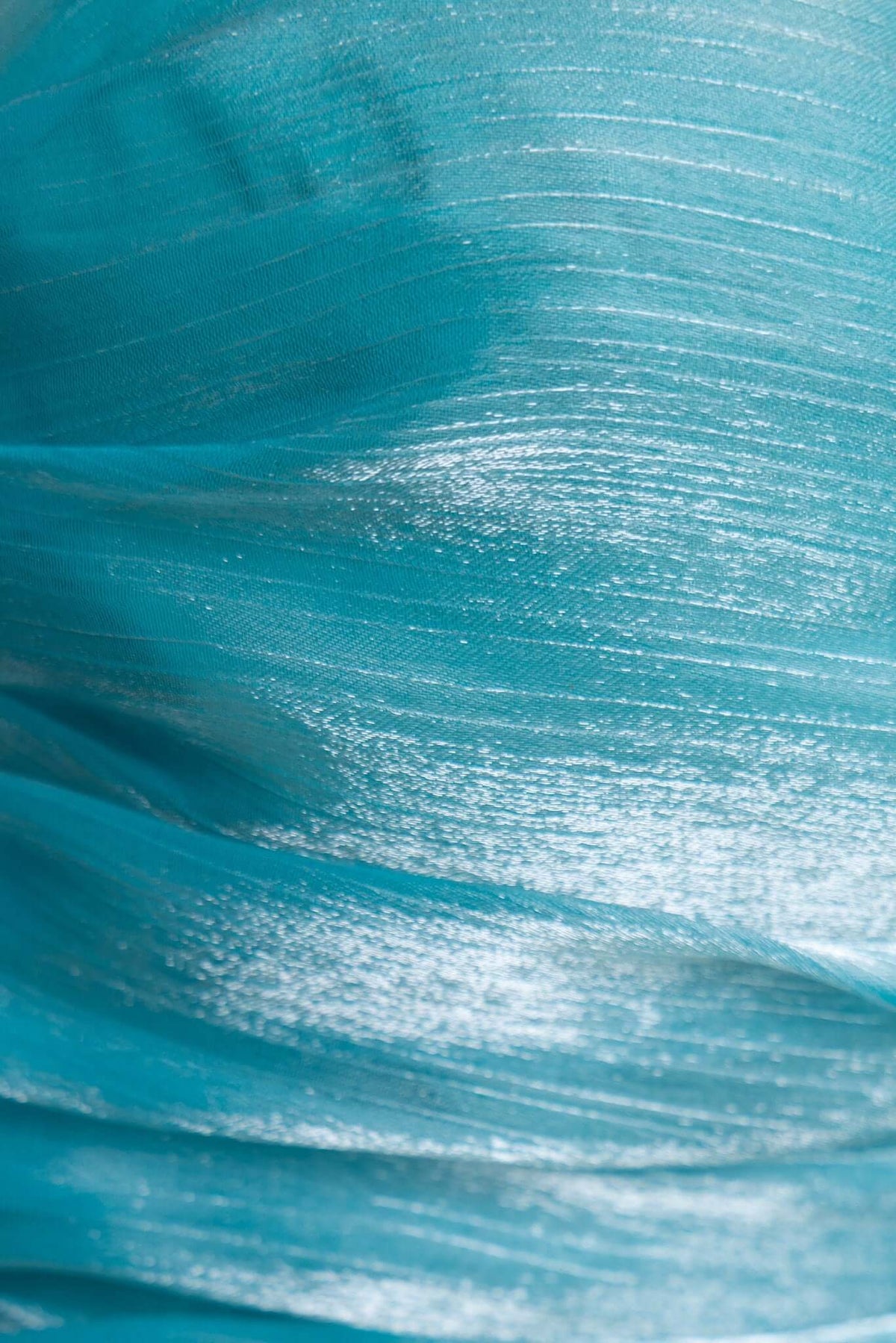 Close-up of shimmering teal fabric with soft texture, ideal for elegant dress designs.