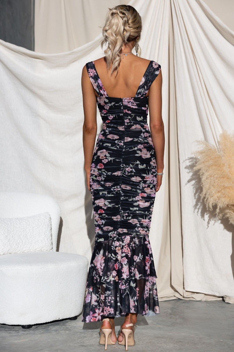 Back view of a floral maxi dress with ruched design and asymmetric hem, perfect for elegant occasions.