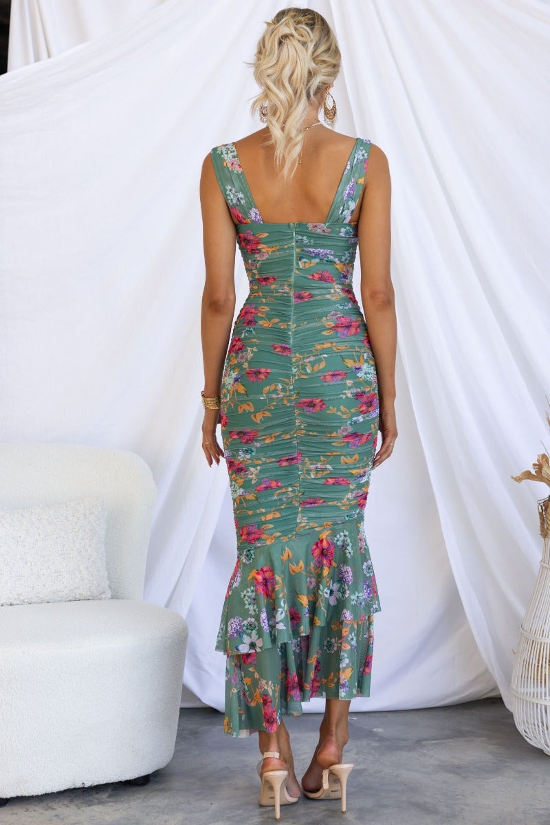 Back view of green floral ruched maxi dress with asymmetric ruffle hem and adjustable straps.