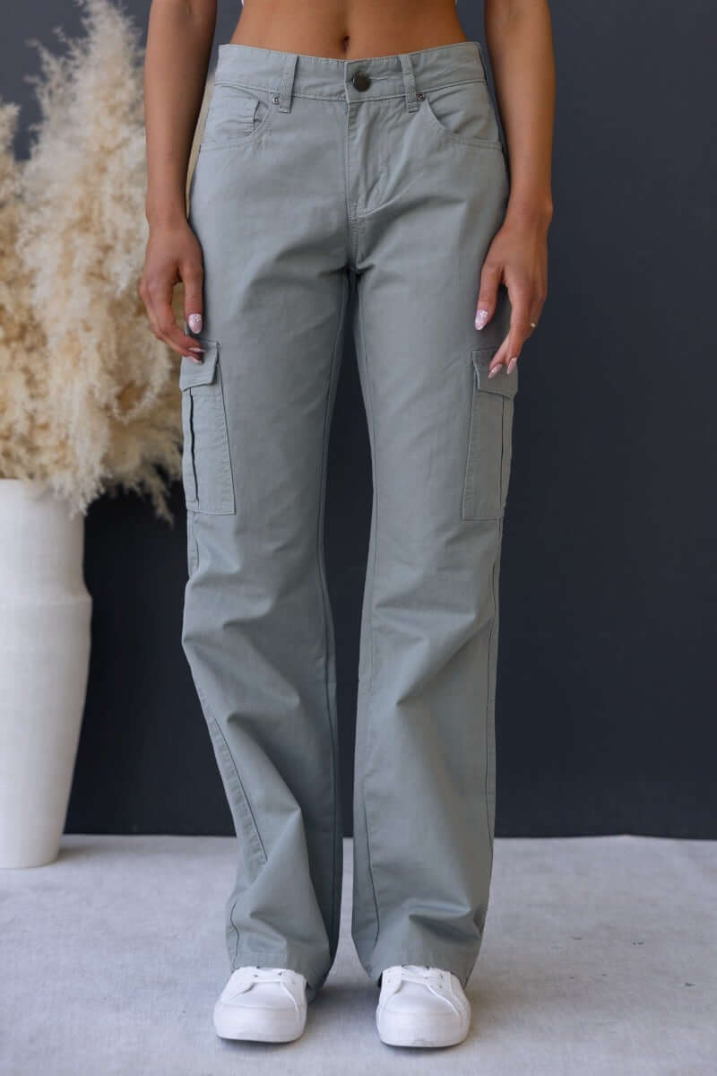Bowie cargo pants in light green with wide legs and multiple pockets, modeled with a bare midriff against a dark background.
