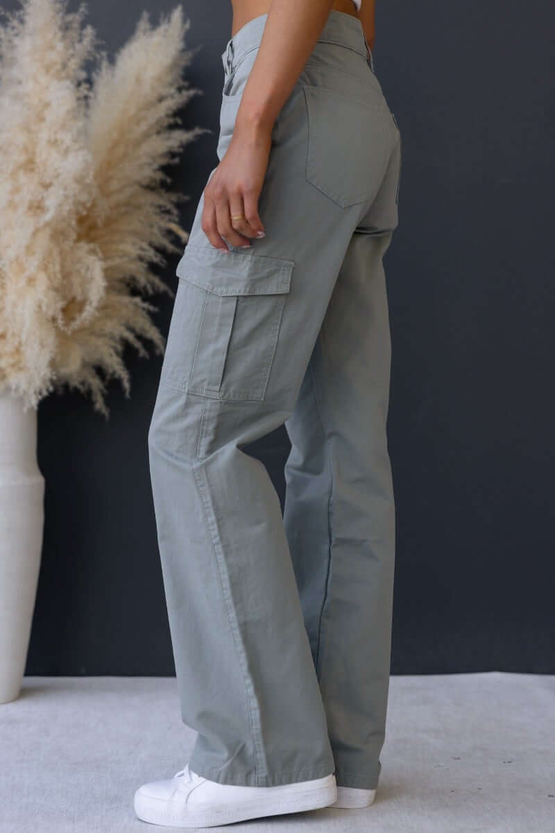 Side view of Bowie Cargo Pants in light green, featuring wide legs and multiple pockets, styled casually.