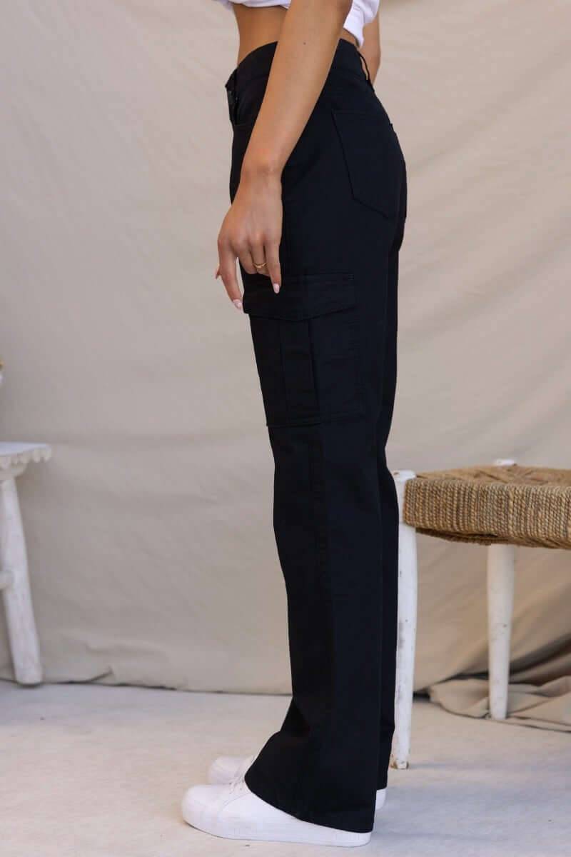 Side view of Bowie Cargo Pants in black, featuring pockets and wide legs, styled with a casual top.