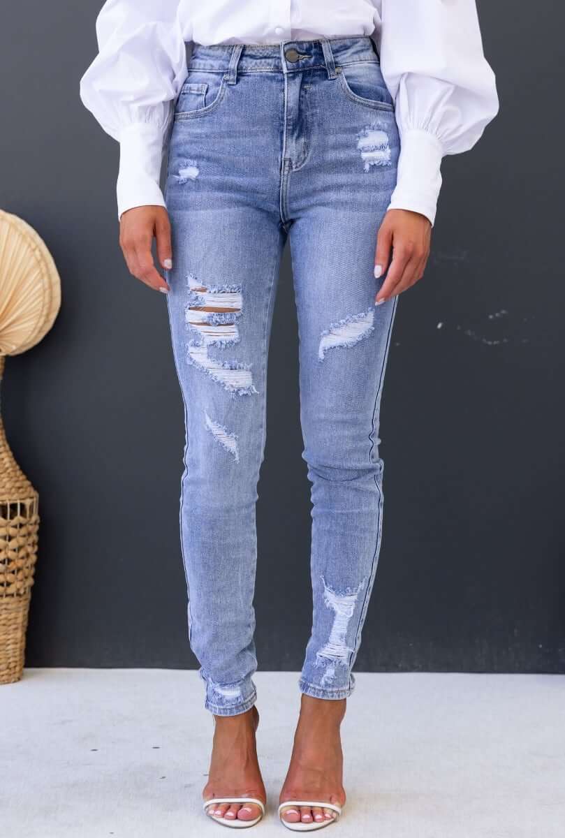 Mecka Jeans: Distressed mid-high waist denim jeans with pockets, featuring a standard skinny fit and stretch material.