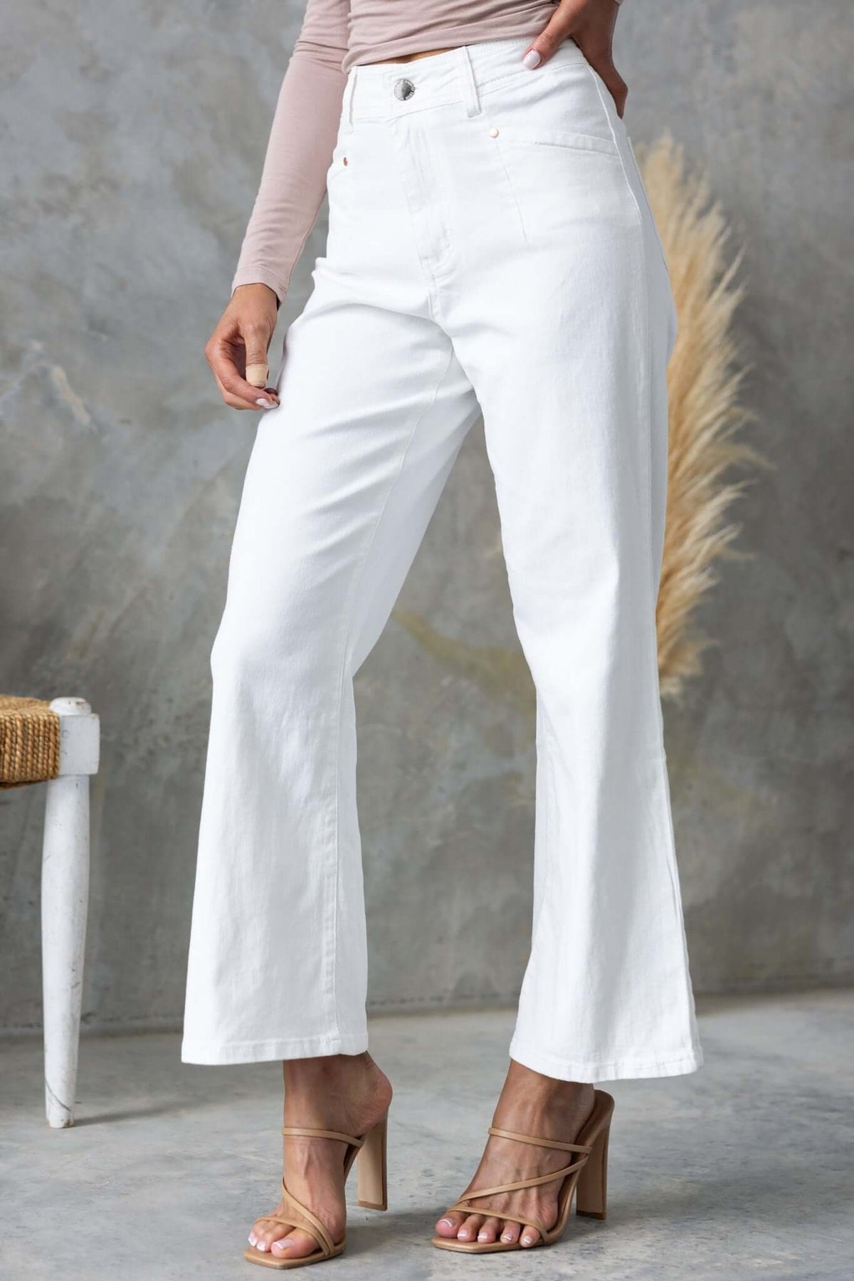 Blanca Jeans: White mid-high waist denim jeans with wide legs and front & back pockets, styled with heels.