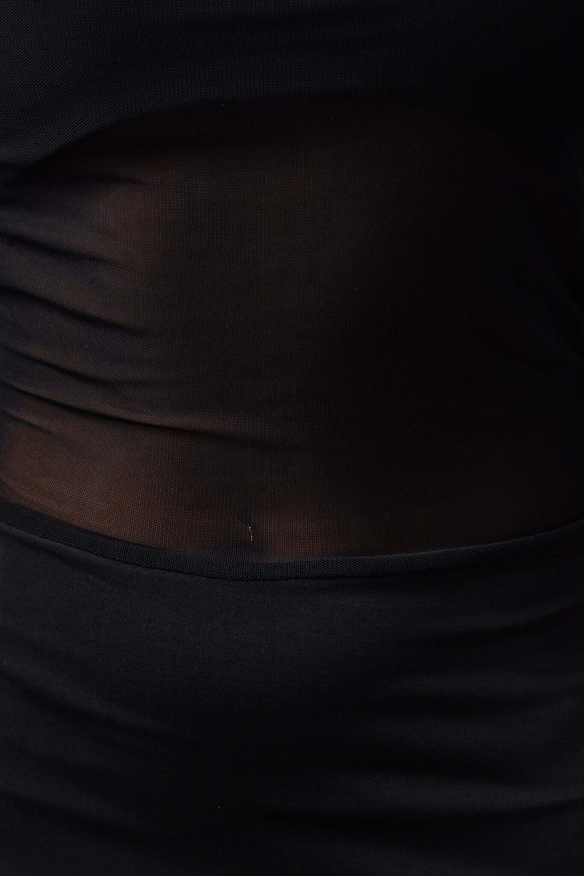 Close-up of the sheer panel detail on the waist of a black maxi dress, highlighting its stylish design.