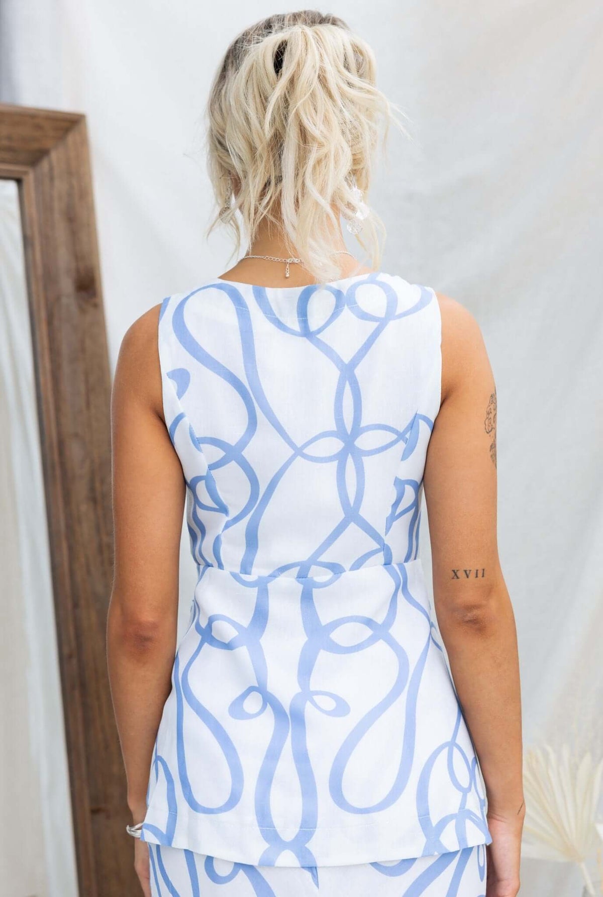 Back view of a woman wearing the Bexley Top featuring a blue abstract design and a sleeveless, relaxed fit.