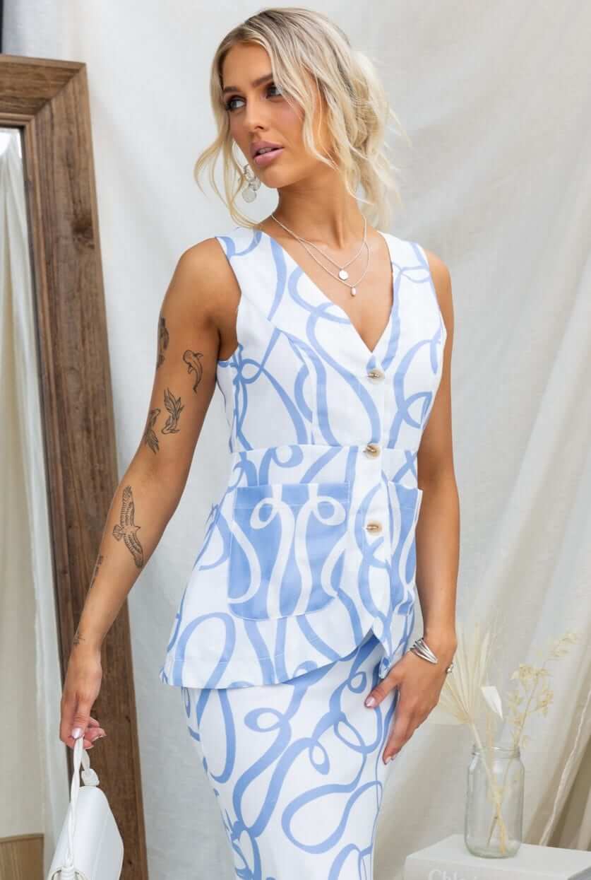 Model wearing Bexley Top in soft blue linen with V-neckline, button-up front, and stylish pockets.