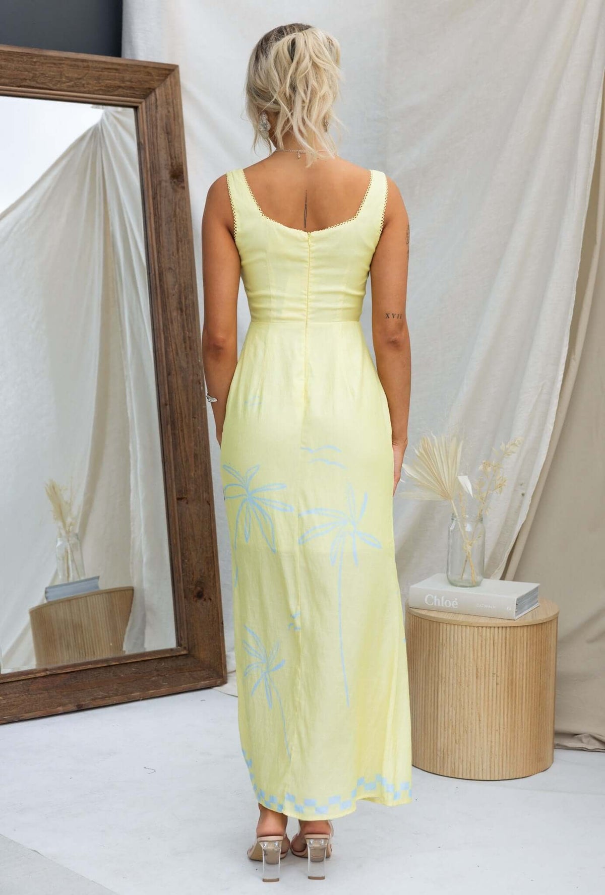 Back view of the Norris Maxi Dress in yellow with floral accents, showcasing its elegant design and flattering fit.