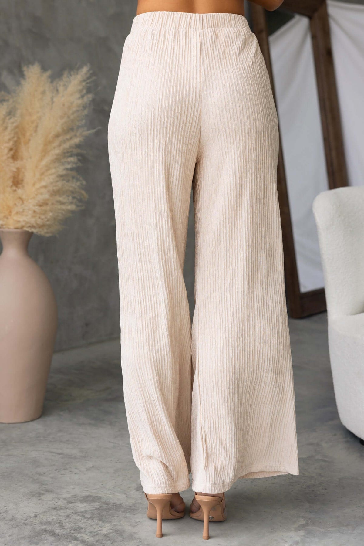 Back view of Lisa Pants in light beige, featuring a mid-high waist and lined design, styled with a chic backdrop.