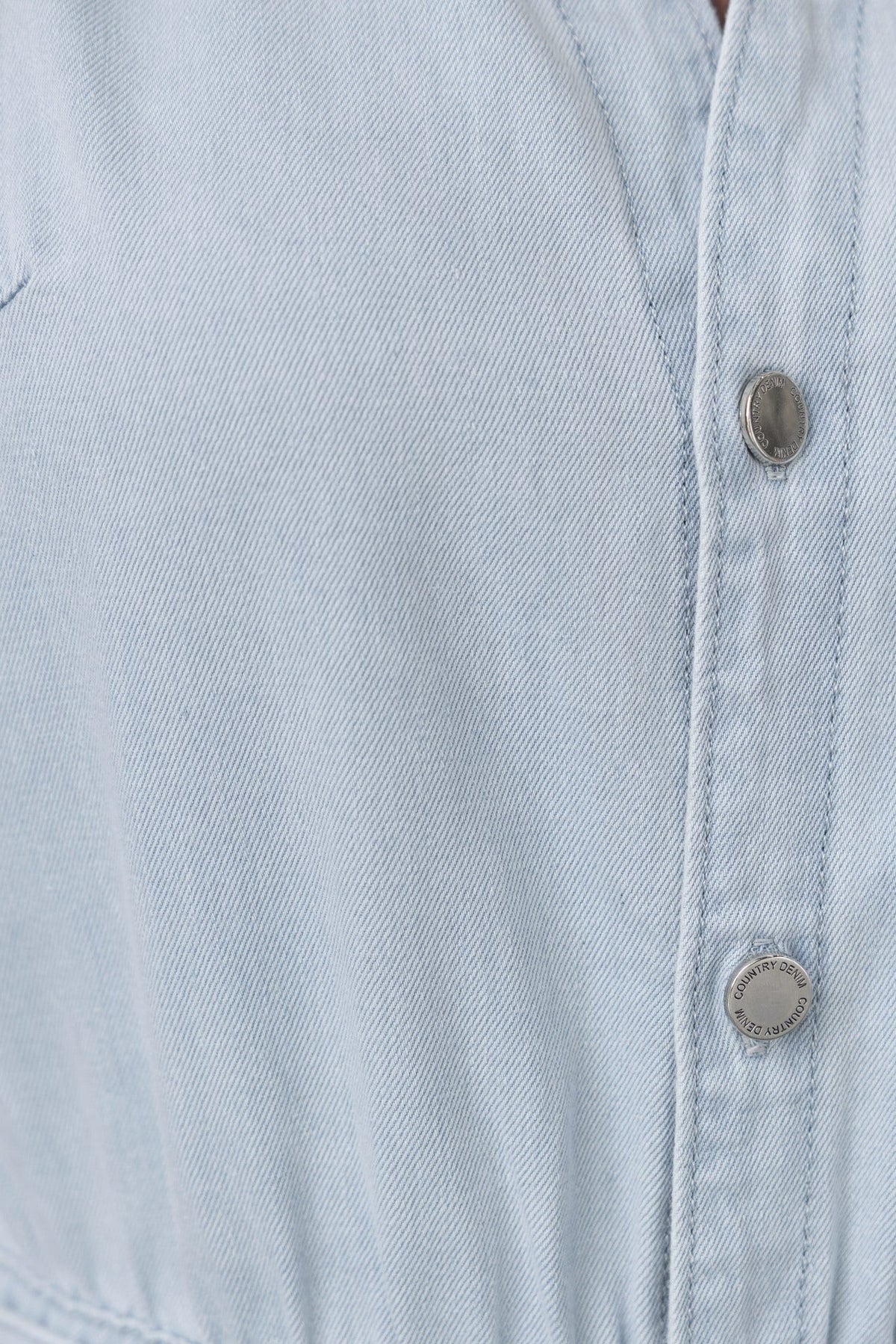 Close-up of the Connie Denim Playsuit's light denim fabric and button-up front detail.