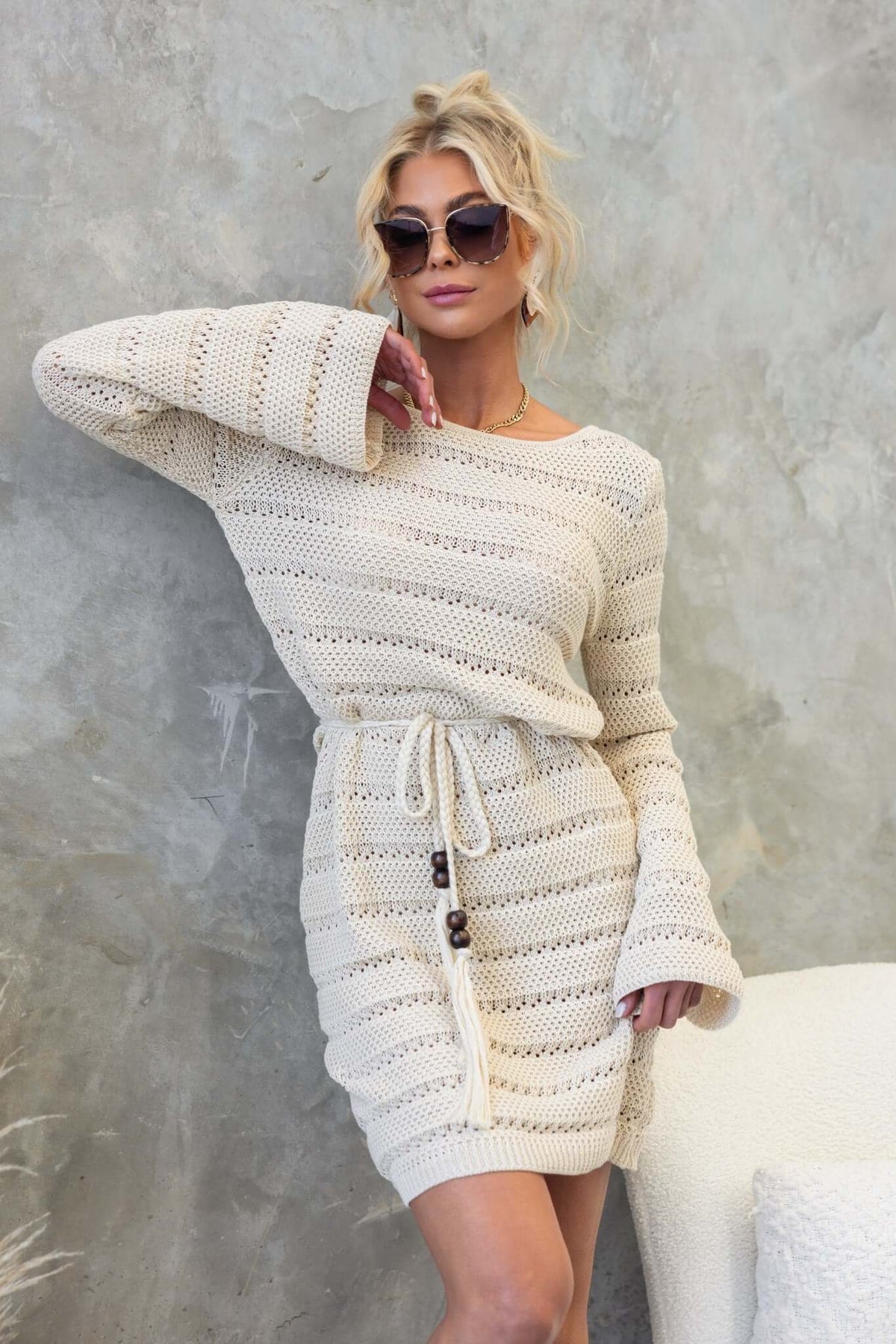 Model wearing the Dunne Dress featuring crochet material, round neckline, and removable tie, styled with sunglasses.