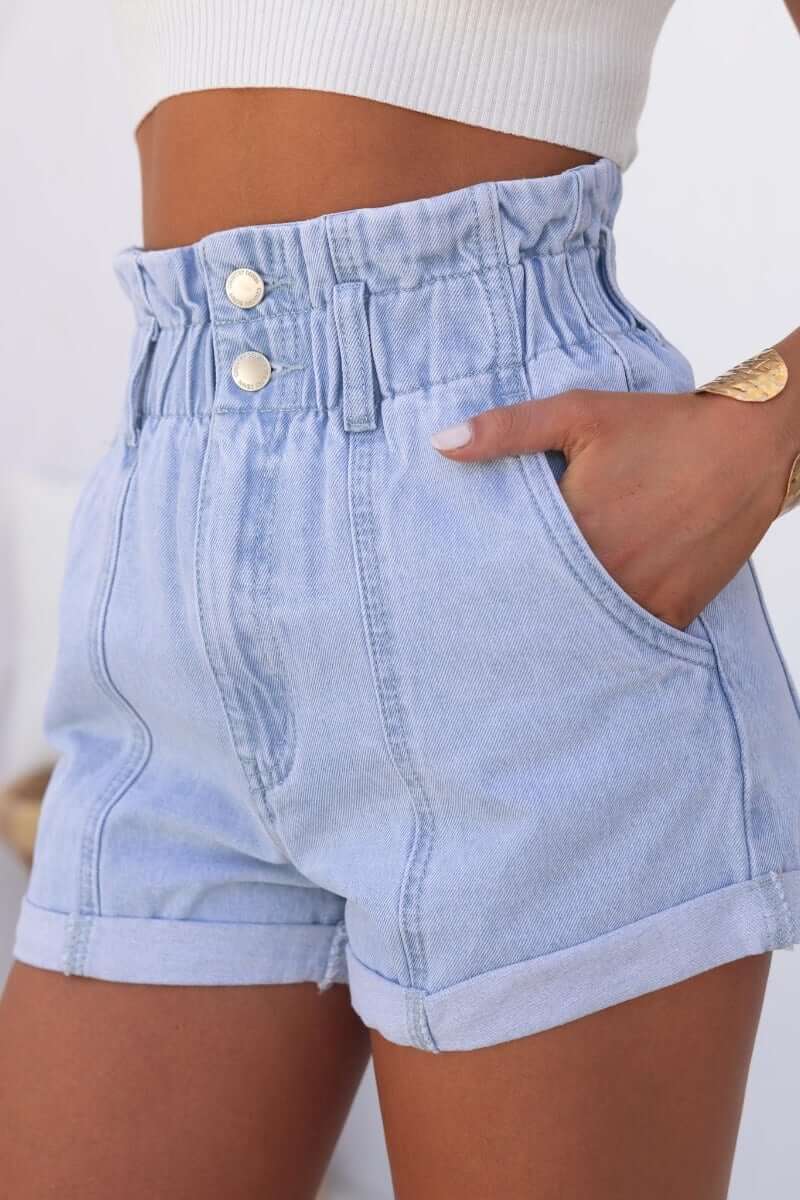 Hattie Paper Bag Shorts featuring a denim paperbag waist, two-button closure, and side pockets in light blue.