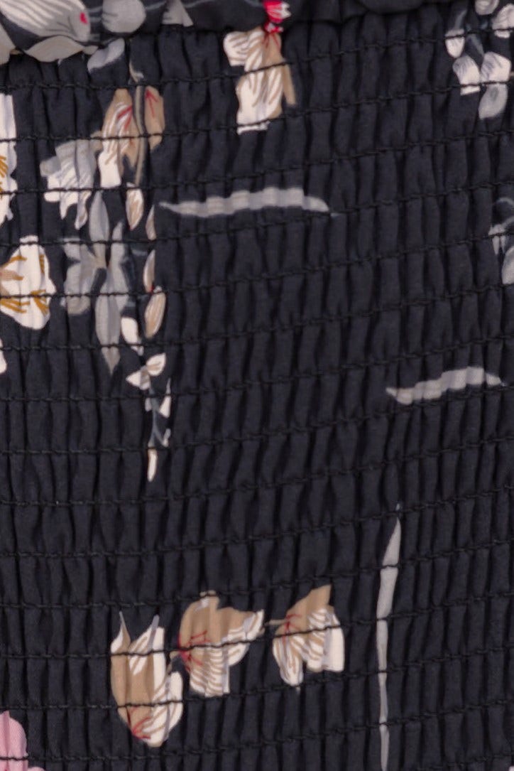 Close-up of Arabella Midi Dress, featuring floral print and elastic smocking in dark fabric.