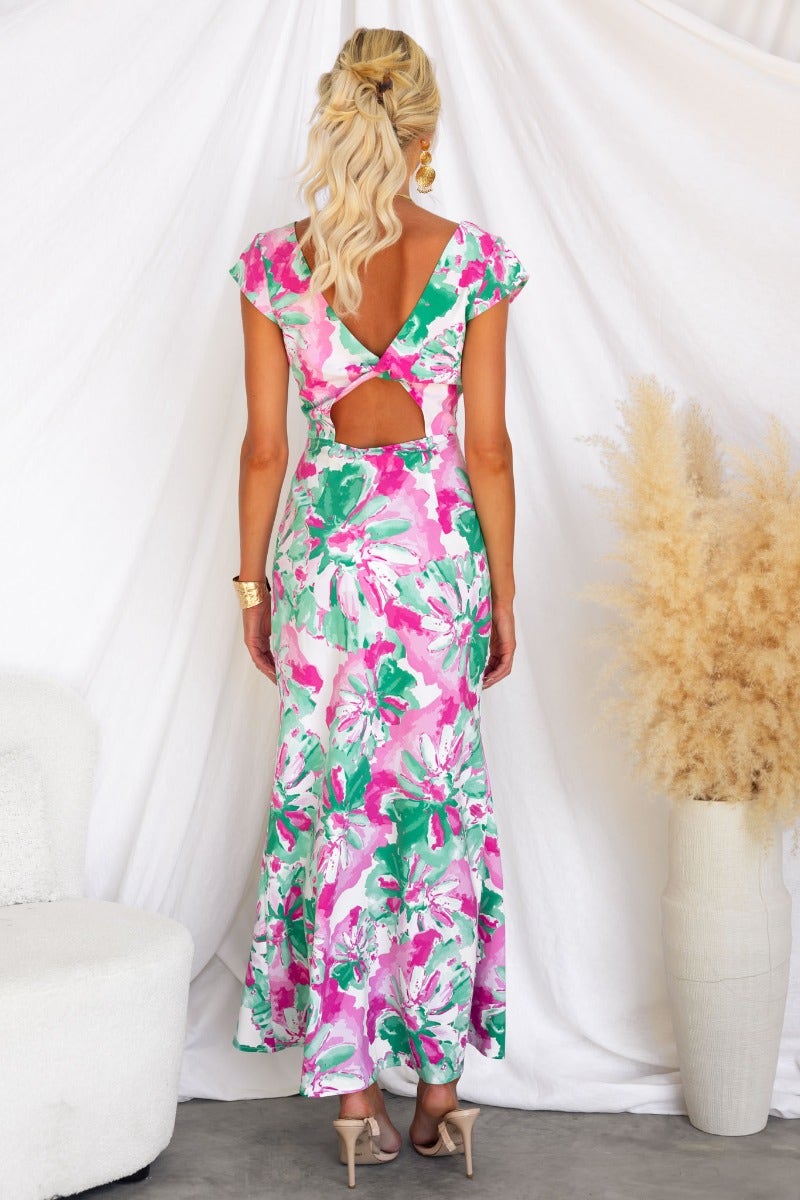 Model wearing a floral print maxi dress with cap sleeves and a twist-back detail, showcasing a vibrant tropical design.