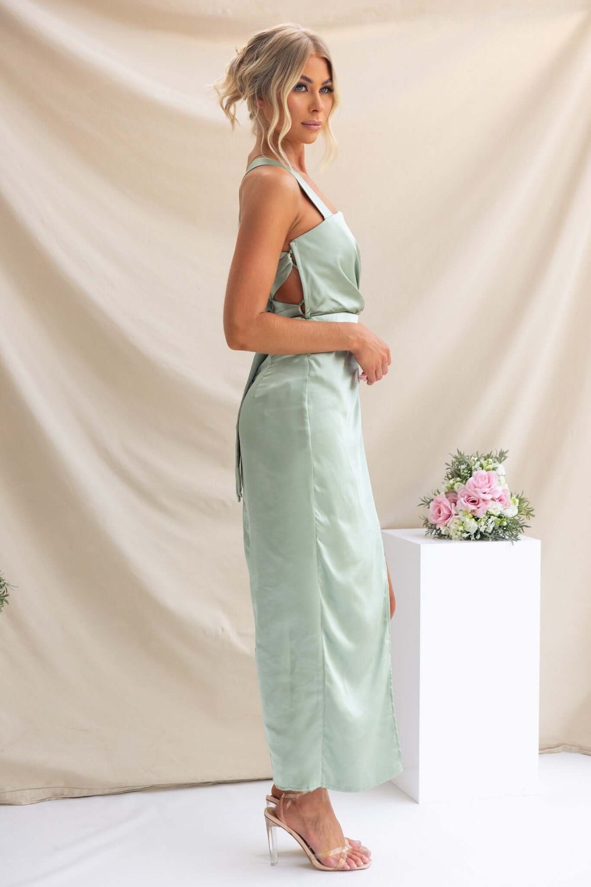 Model wearing a light green Merritt Maxi Dress with adjustable tie straps, showcasing the elegant side profile.