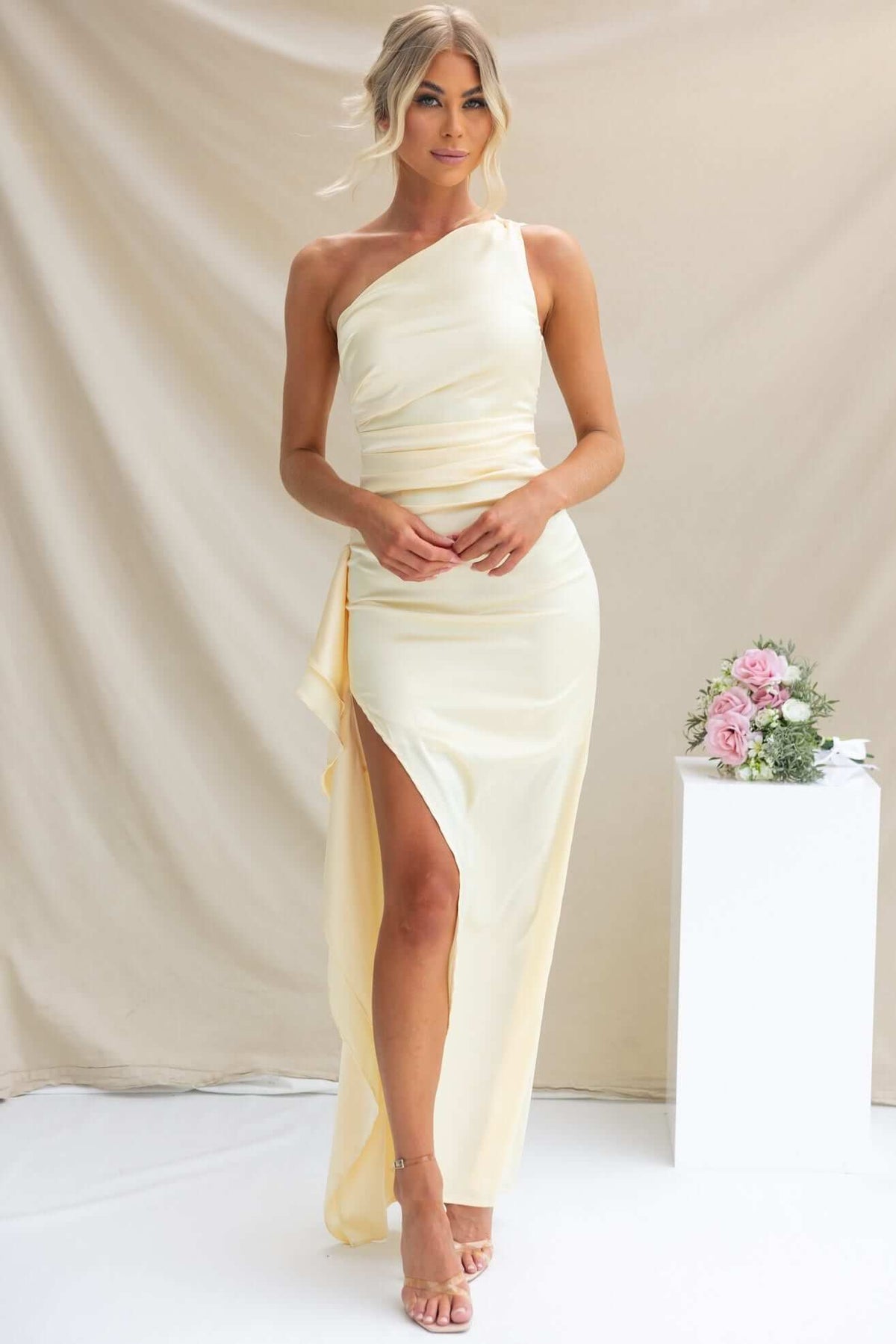 Dimmi Maxi Dress in soft yellow satin with one-shoulder neckline and asymmetrical hemline, showcased by a model.