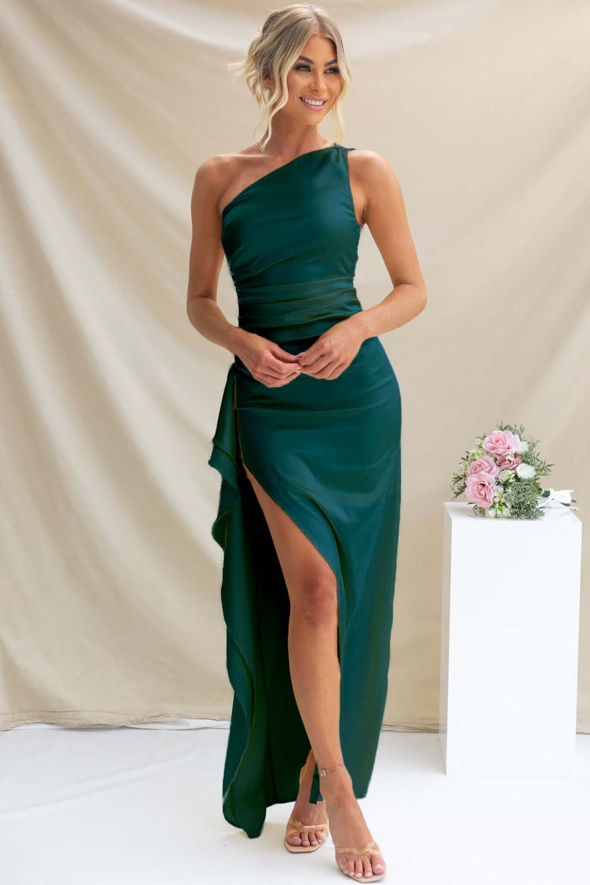 Model wearing Dimmi Maxi Dress in green satin, featuring a one-shoulder neckline and ruffle trim, ideal for special occasions.