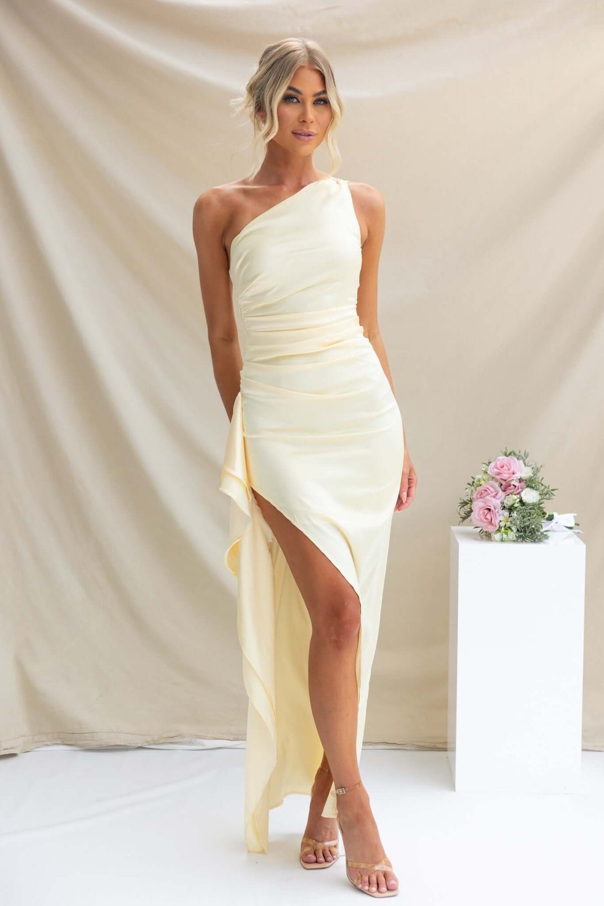 Elegant one-shoulder satin maxi dress in yellow with asymmetrical hemline and thigh-high slit.