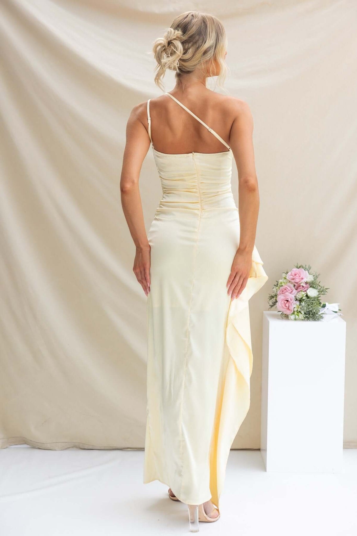 Back view of Dimmi Satin Maxi Dress featuring a one-shoulder neckline and asymmetrical hemline with ruffle trim.
