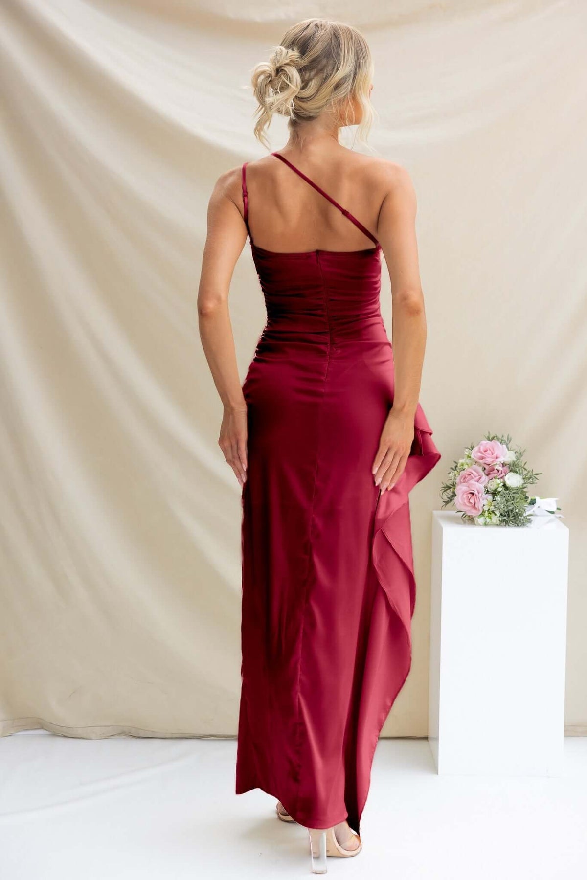 Back view of the Dimmi Maxi Dress, featuring a one-shoulder neckline and ruffle trim detail in a stunning burgundy shade.