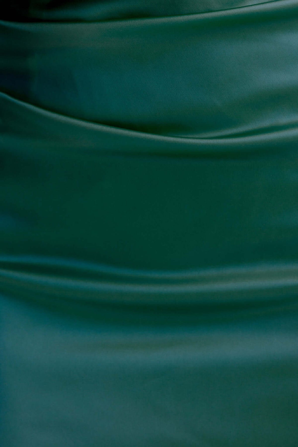 Close-up of dark green satin fabric showcasing elegant draping intended for a Dimmi maxi dress.