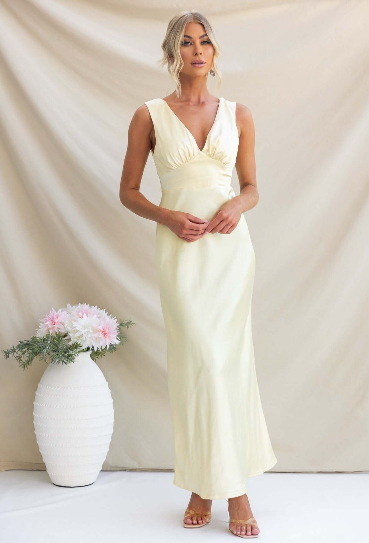 Alika Maxi Dress in soft yellow satin with V-neckline and split back, styled for a bridal look.