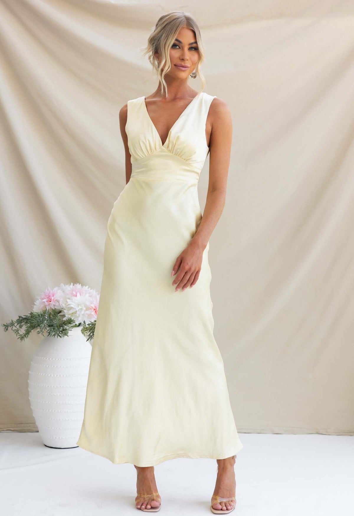 Alika Maxi Dress in soft yellow with V-neckline and fitted silhouette, perfect for elegant occasions.