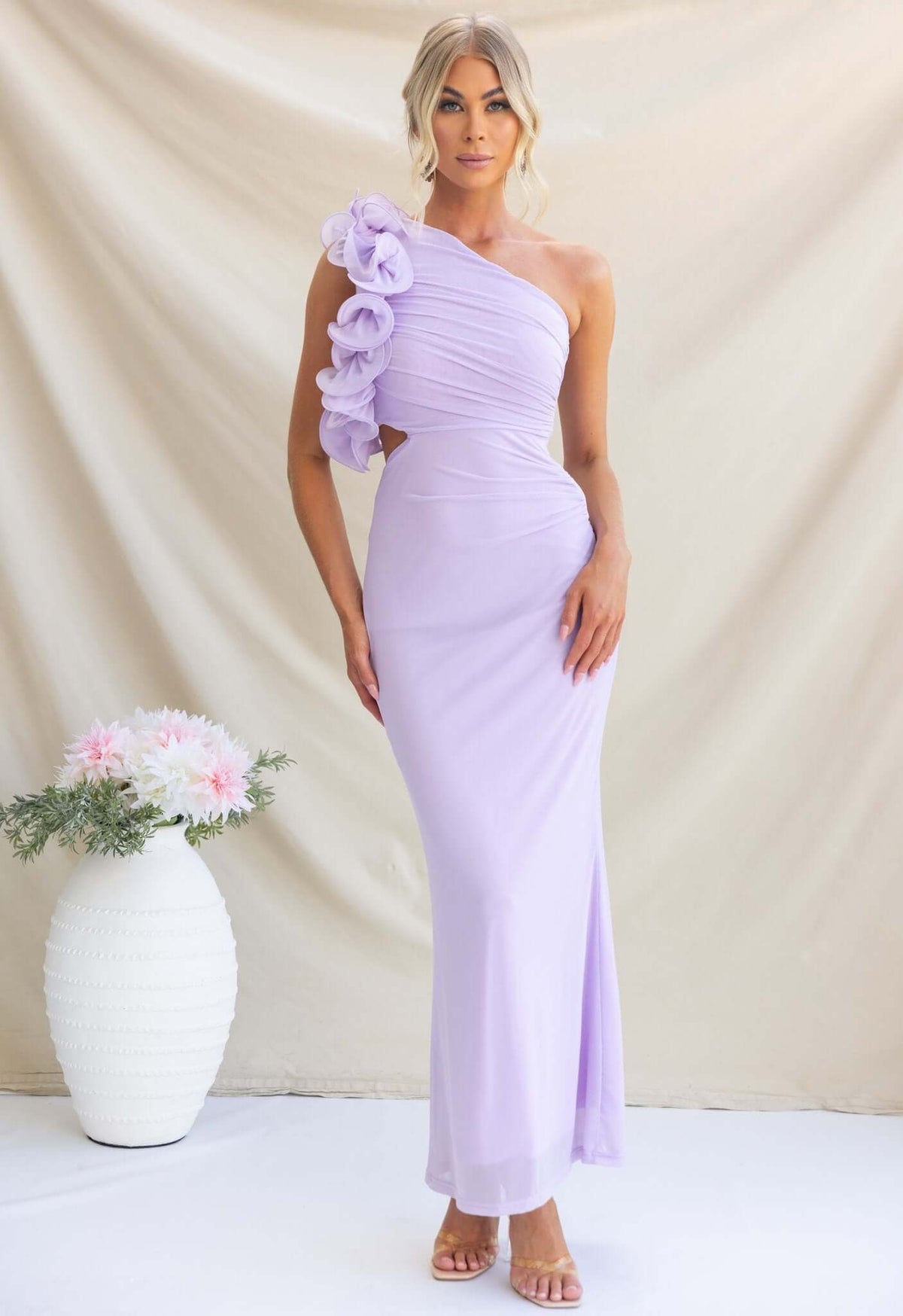 Model in a lavender Meriden Maxi Dress with one-shoulder neckline and floral detail, styled for a special occasion.