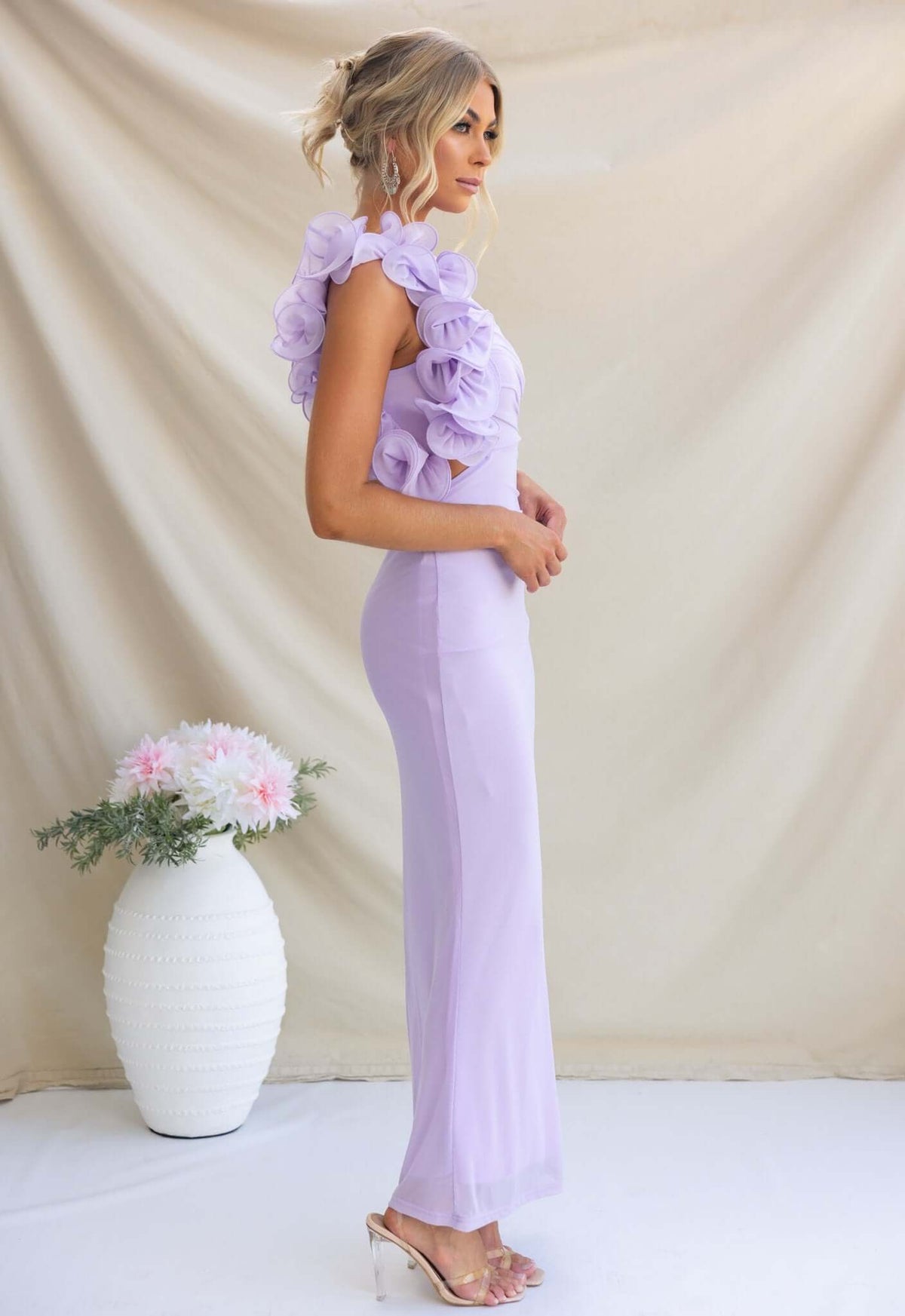 Side view of model wearing Meriden Maxi Dress in lilac with floral ruffles, showcasing elegant fit and style.