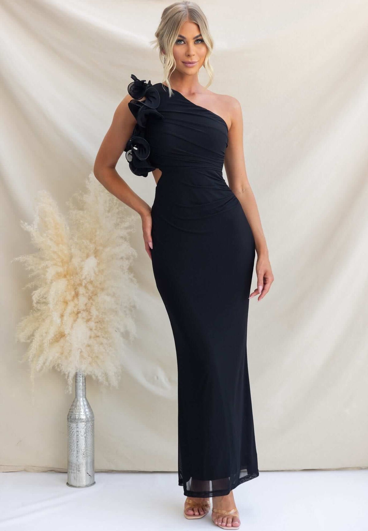 Model wearing Meriden Maxi Dress, a black one-shoulder gown with floral detail and cut-out waist.