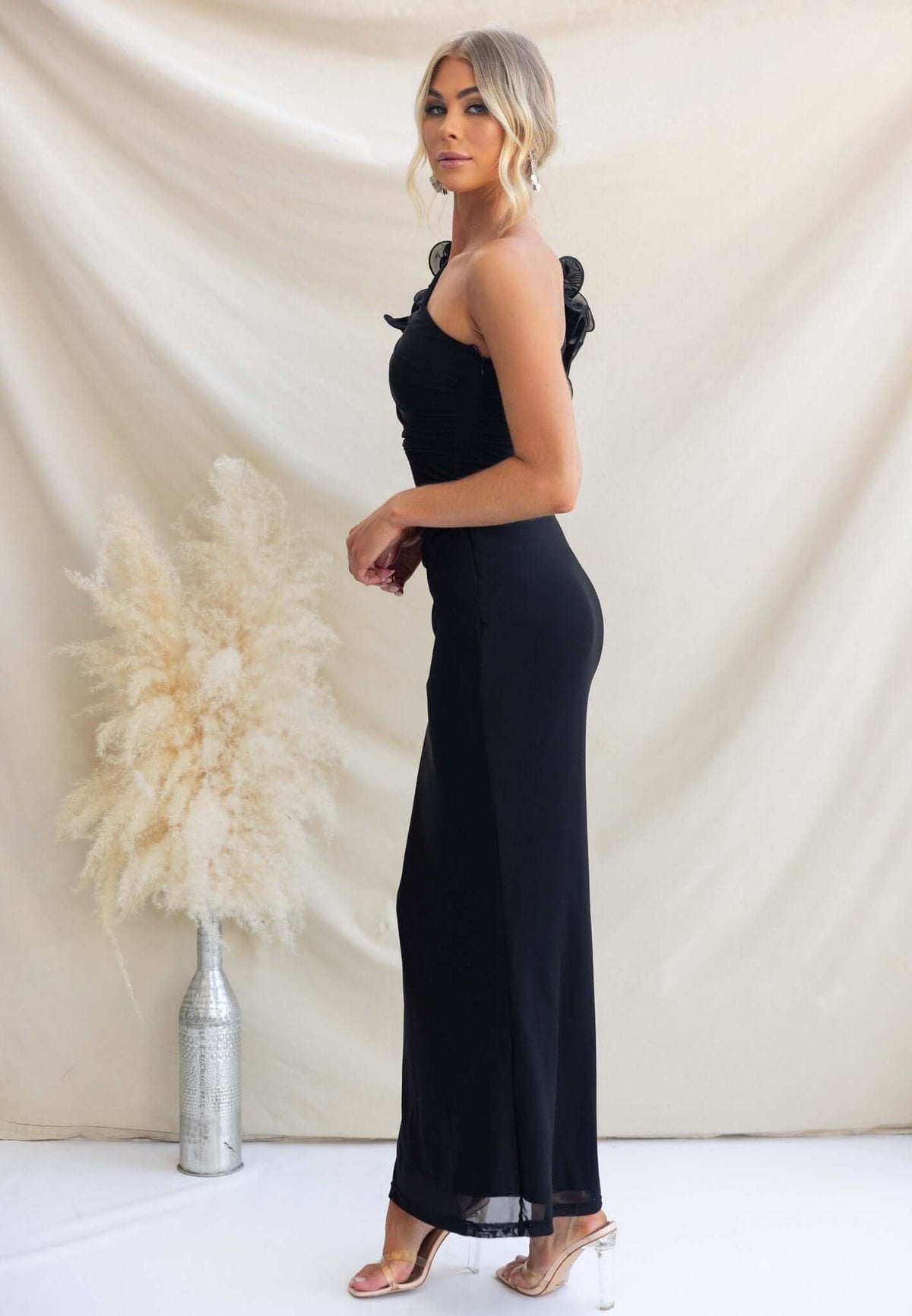 Model wearing the Meriden Maxi Dress in black with one-shoulder design and side cut-out, showcasing a fitted silhouette.