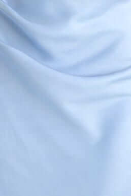 Soft light blue fabric draping elegantly, showcasing a smooth satin texture for fashion apparel.