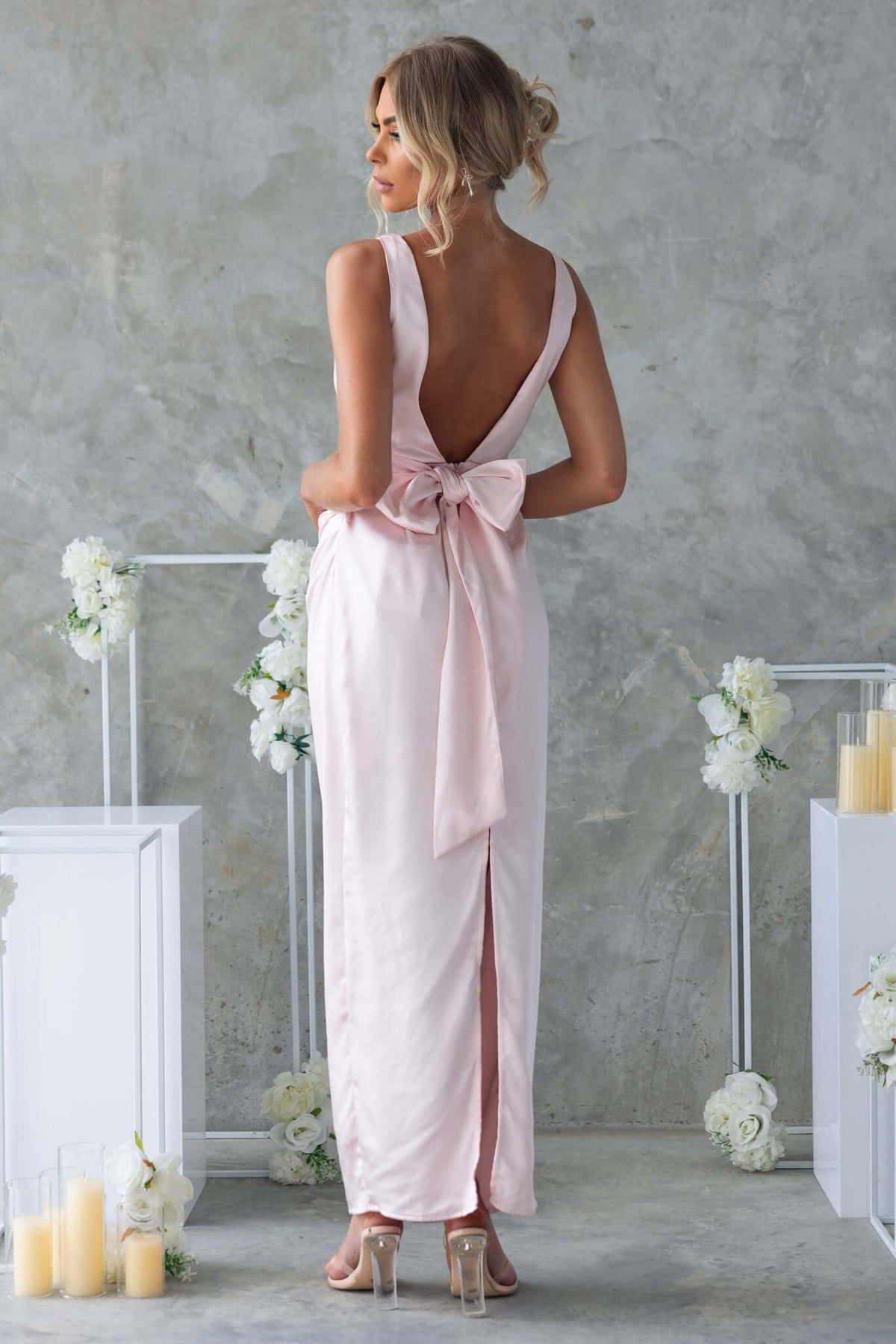 Model wearing Dakari Maxi Dress in pink with a high neckline, back tie detail, and back split.