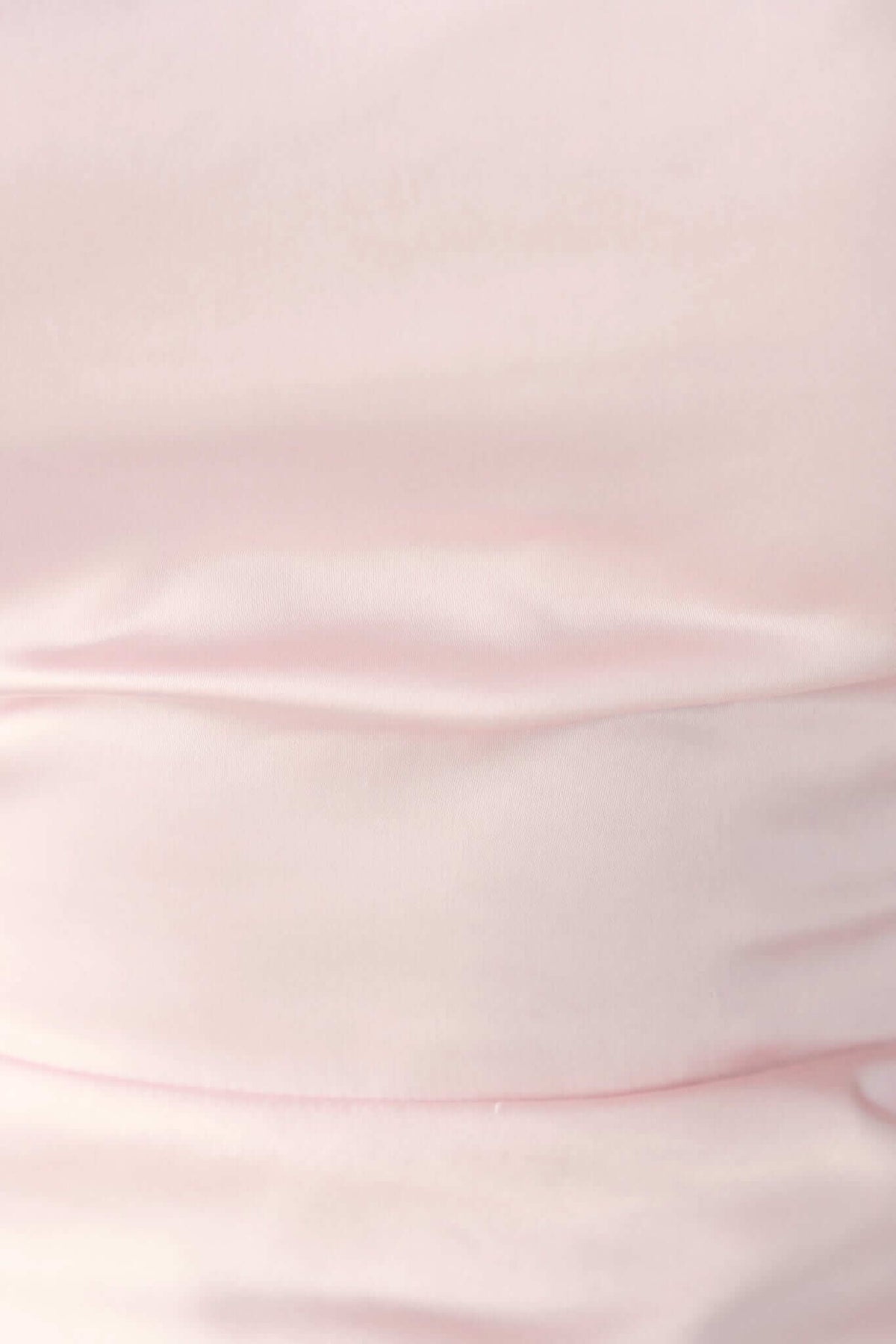 Close-up of the satin fabric of the Dakari Maxi Dress, showcasing its soft pink color and smooth texture.