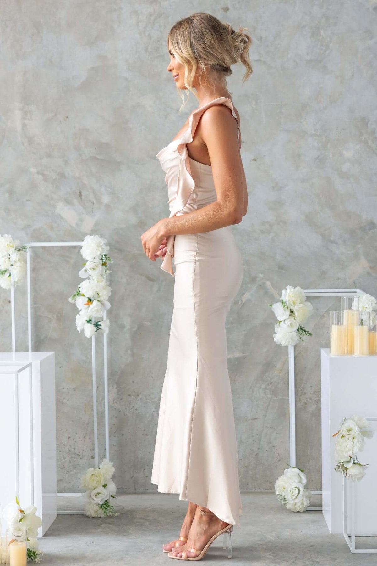 Side view of Ingrid Maxi Dress with adjustable straps and draping in a soft beige color, featuring a subtle fishtail hem.