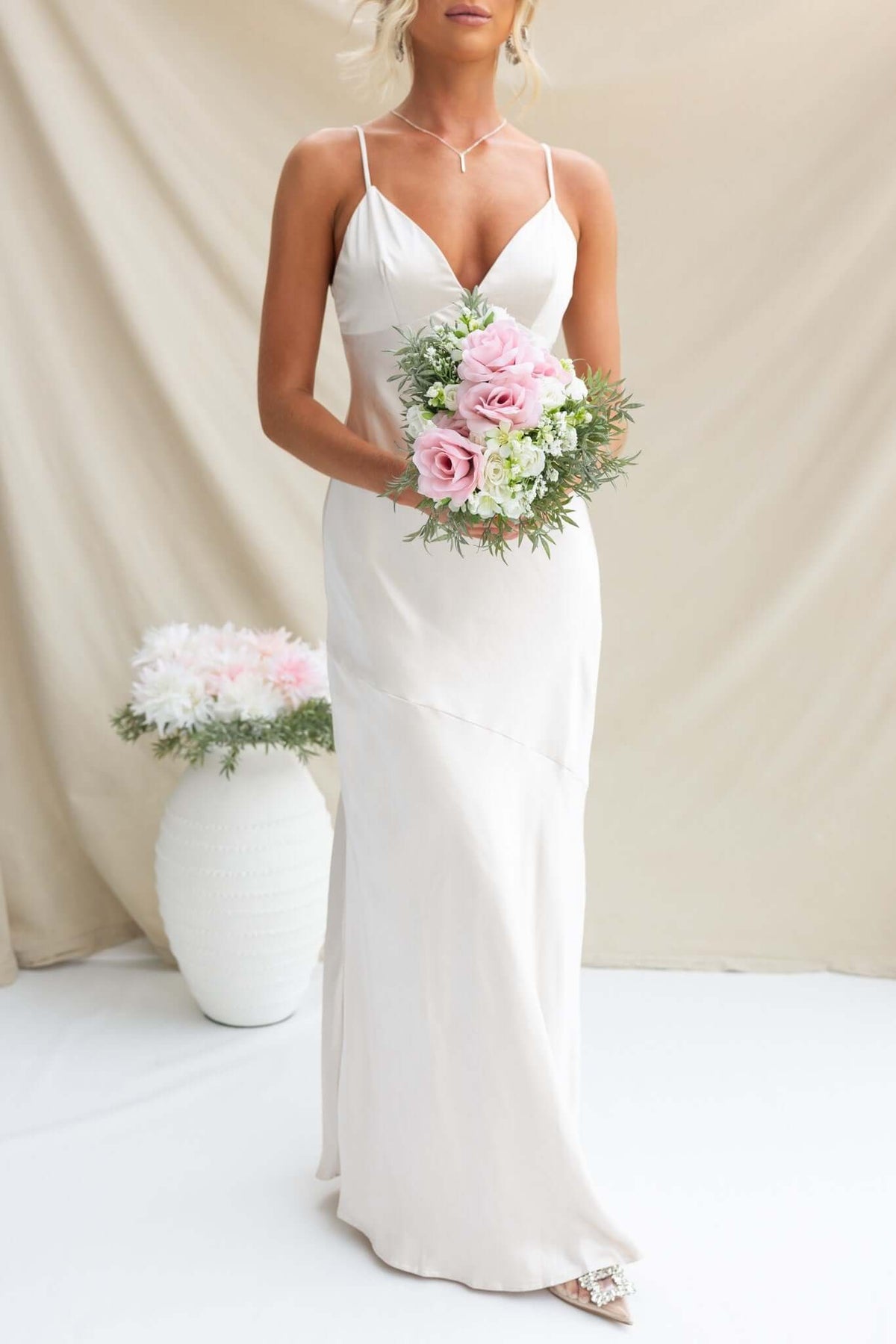 Coralina Maxi Dress with adjustable straps, satin material, worn by model holding pink floral bouquet.