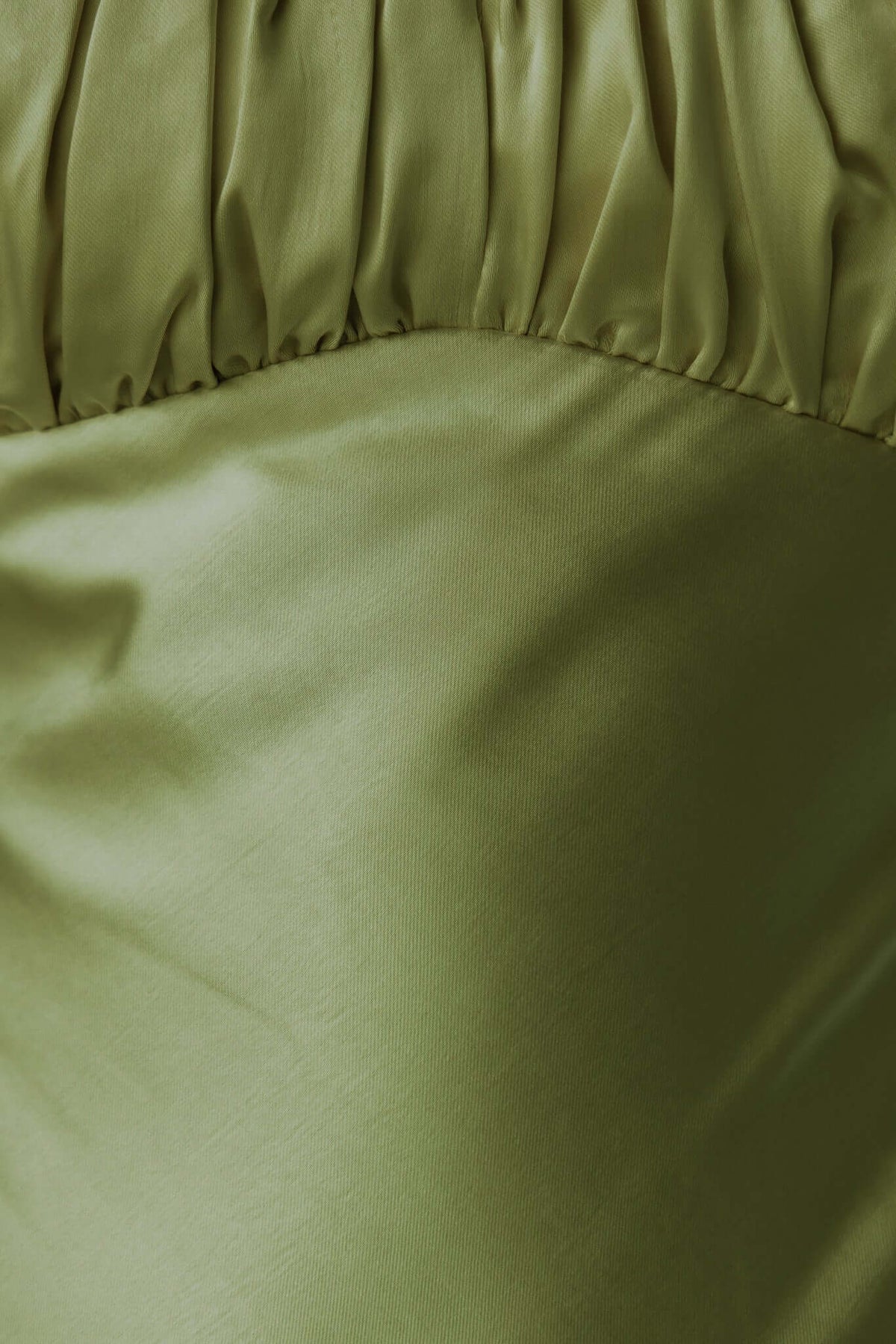 Close-up of luxurious satin fabric in olive green with gathered detail, showcasing the texture of the Celine Maxi Dress.