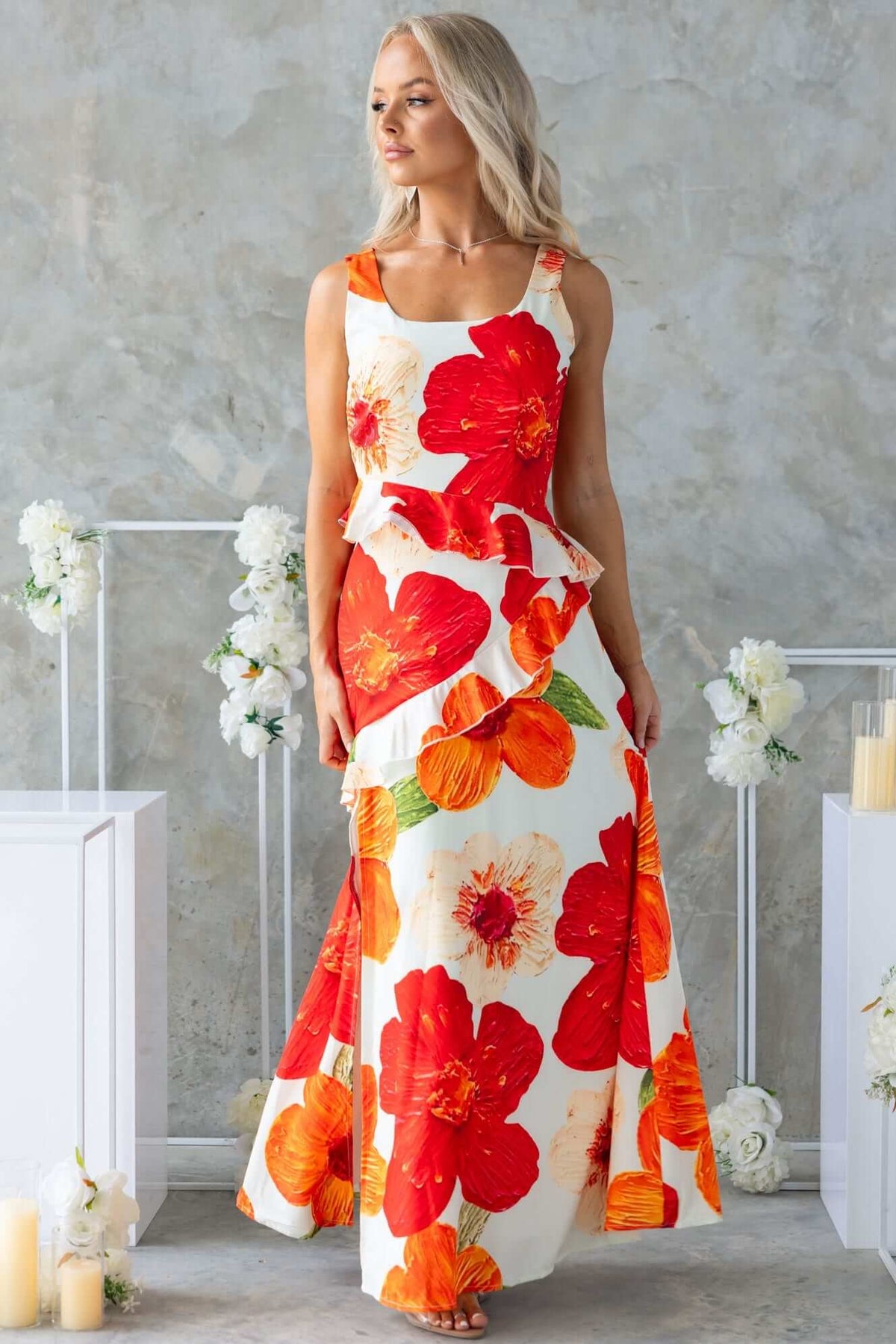 Model wearing a Larni maxi dress with vibrant red and orange floral patterns, showcasing a side zip and front split.
