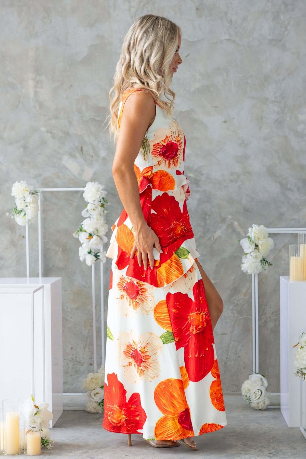 Side view of a woman in a floral Larni Maxi Dress with red and orange flowers, featuring a front split.