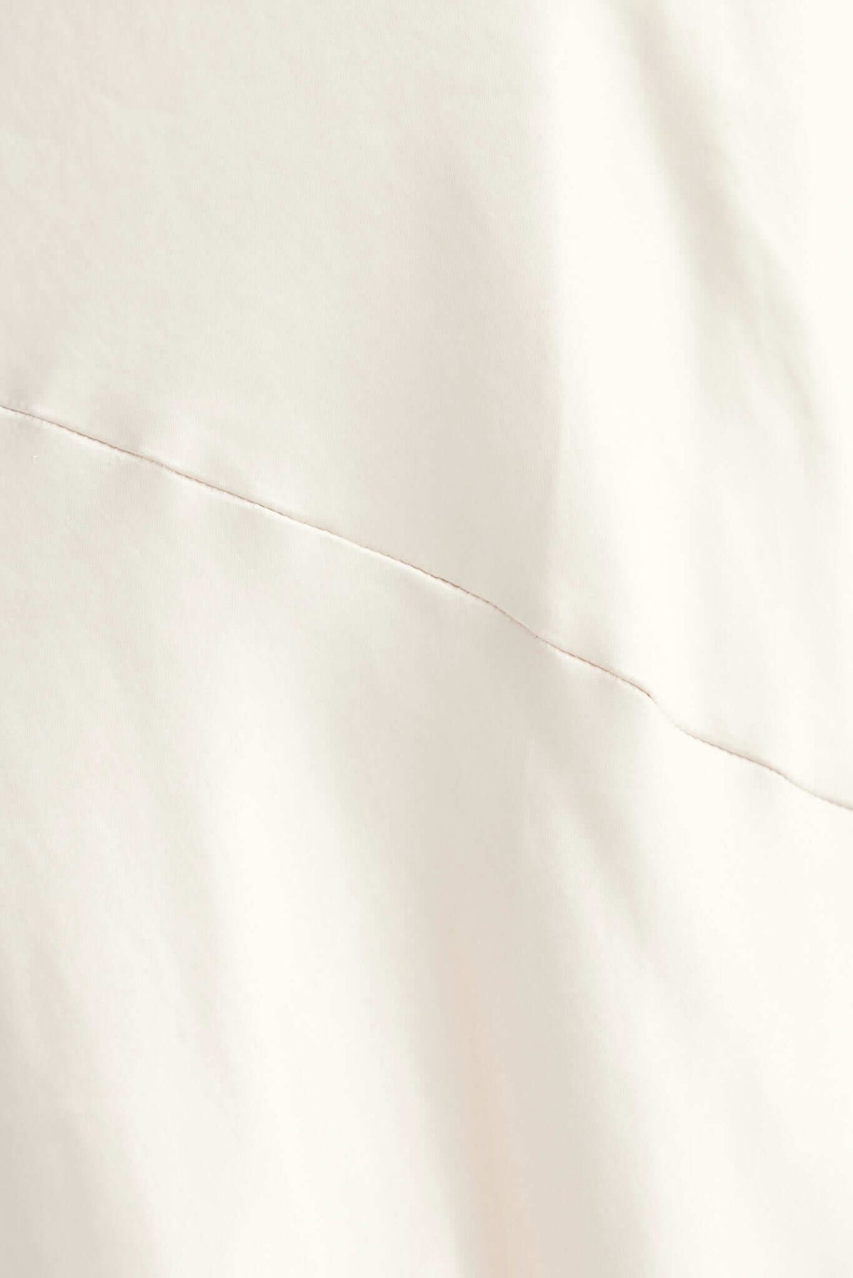 Close-up of smooth satin fabric in a neutral shade, showcasing delicate stitching detail.