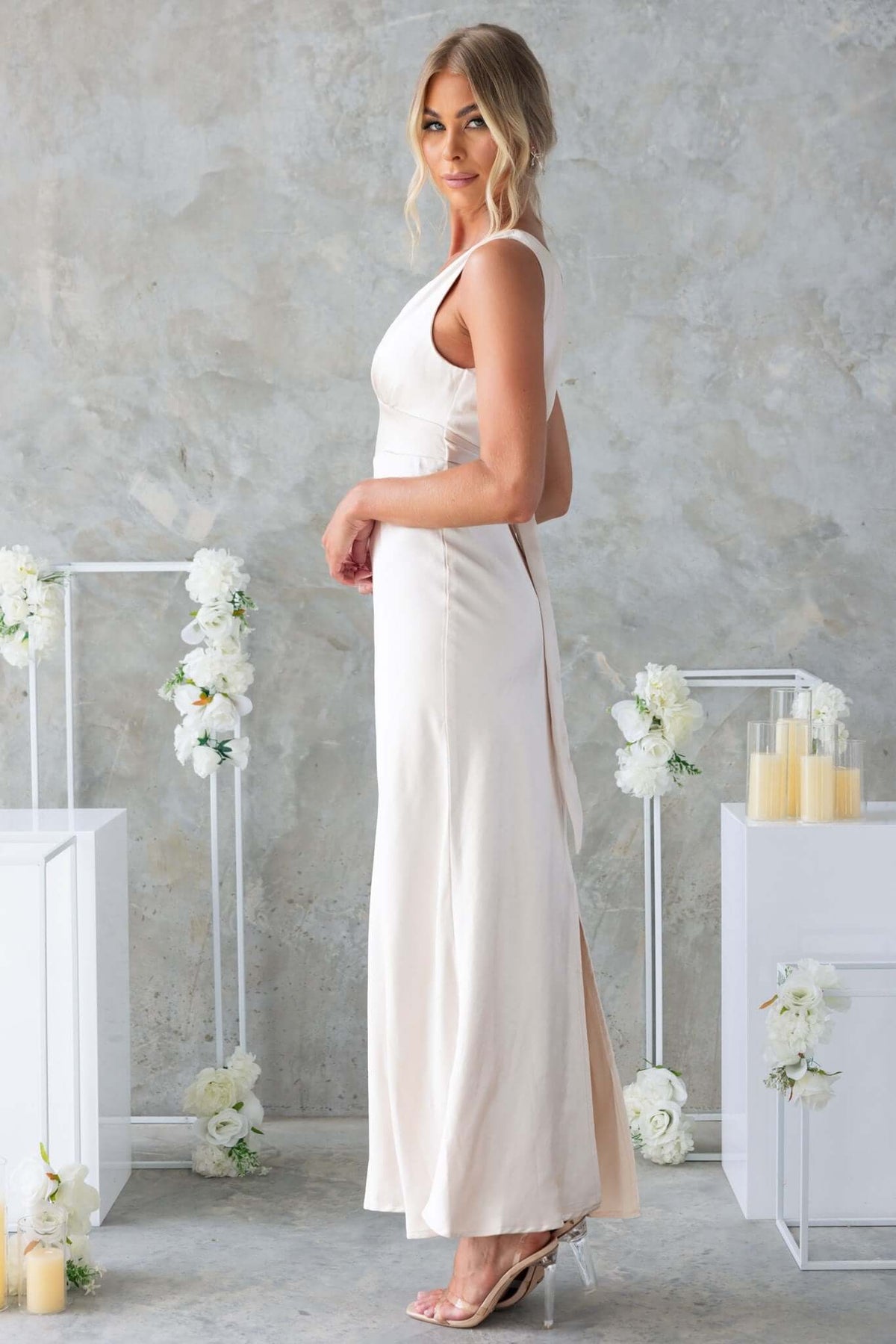 Model wearing Alika Maxi Dress with V-neckline and back split, showcasing elegant satin fabric and a chic silhouette.