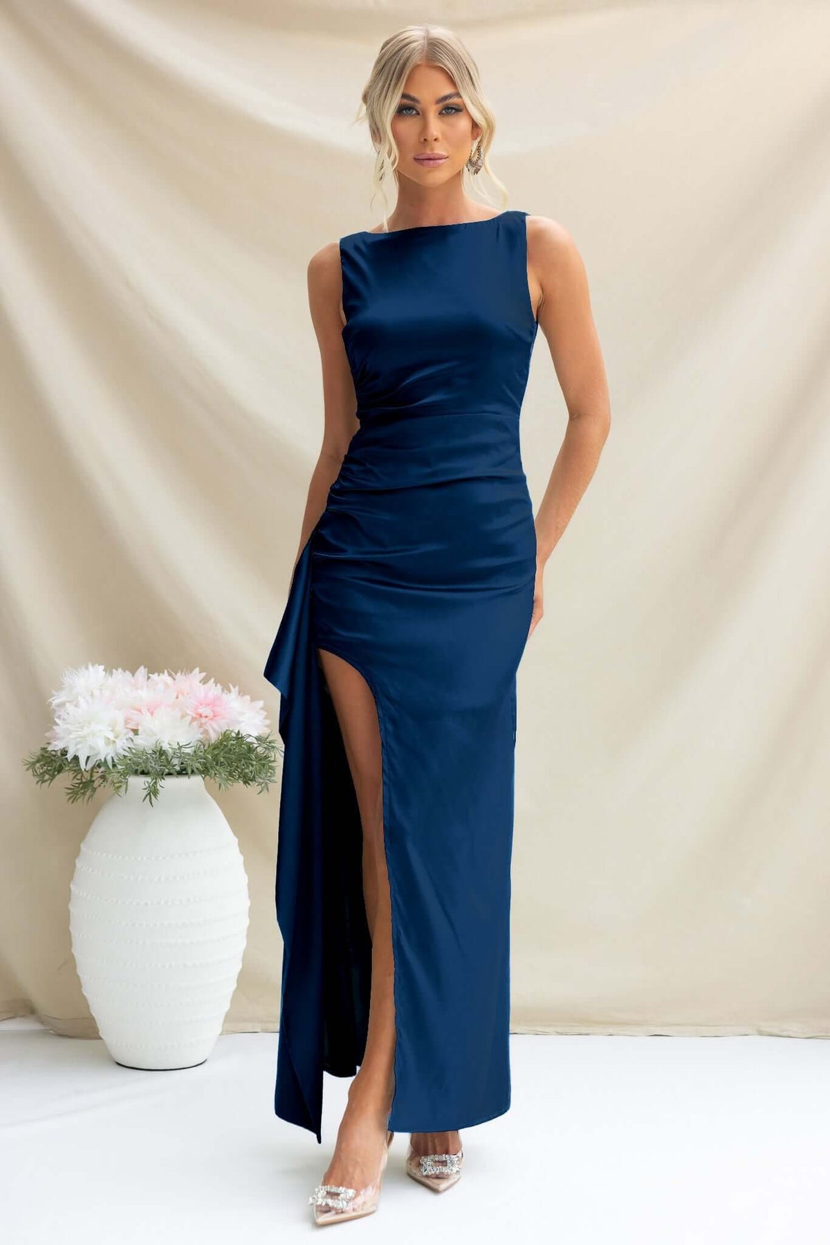 Model wearing Kenzie Maxi Dress in navy satin, featuring a high neckline and side split, styled elegantly with heels.
