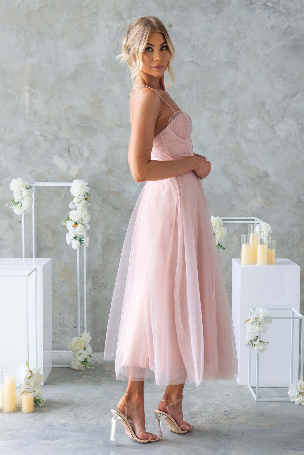 Model wearing the Florence Midi Dress, featuring a fitted bodice and tulle skirt in soft pink, showcasing elegance and style.